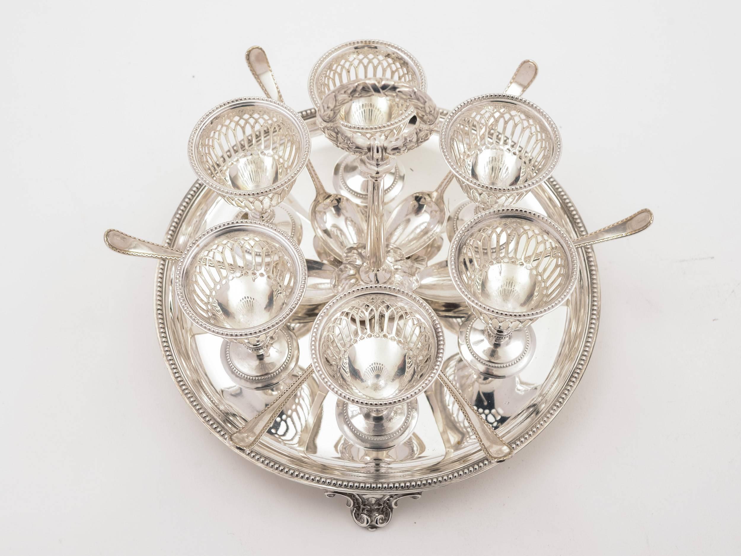 A stunning English Victorian six person silver plated egg cruet with beaded decoration to edge of base, pierced and beaded decoration to egg cups and which sits on cast feet. The carrying handle is modelled on a wreath and there are six accompanying