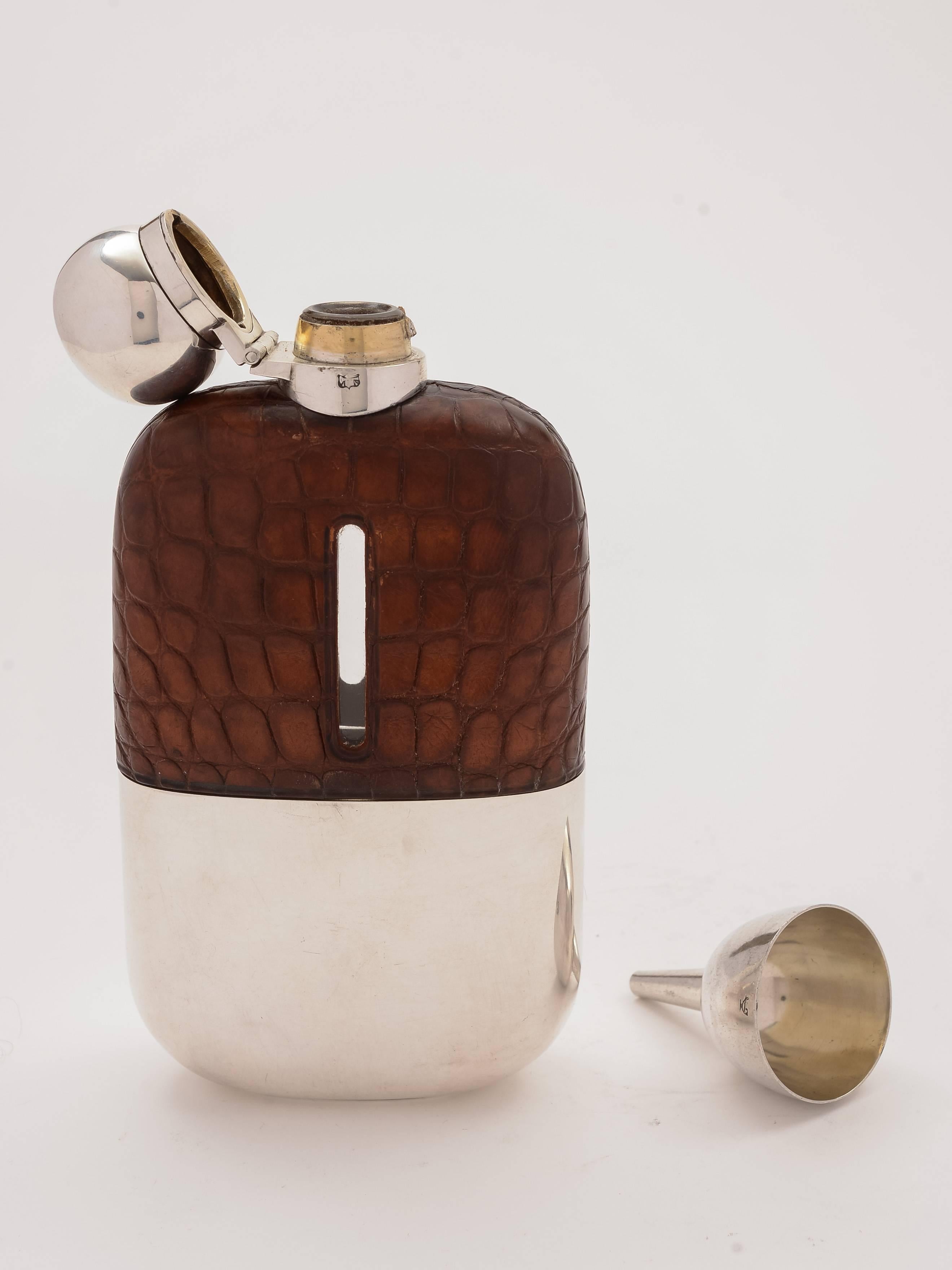 A nice English Edwardian silver plated hip flask with crocodile leather cover, bayonet top and pull-off cup with original gilded interior. Also comes with silver plated filling funnel, circa 1905. Made by the renowned maker James Dixon &