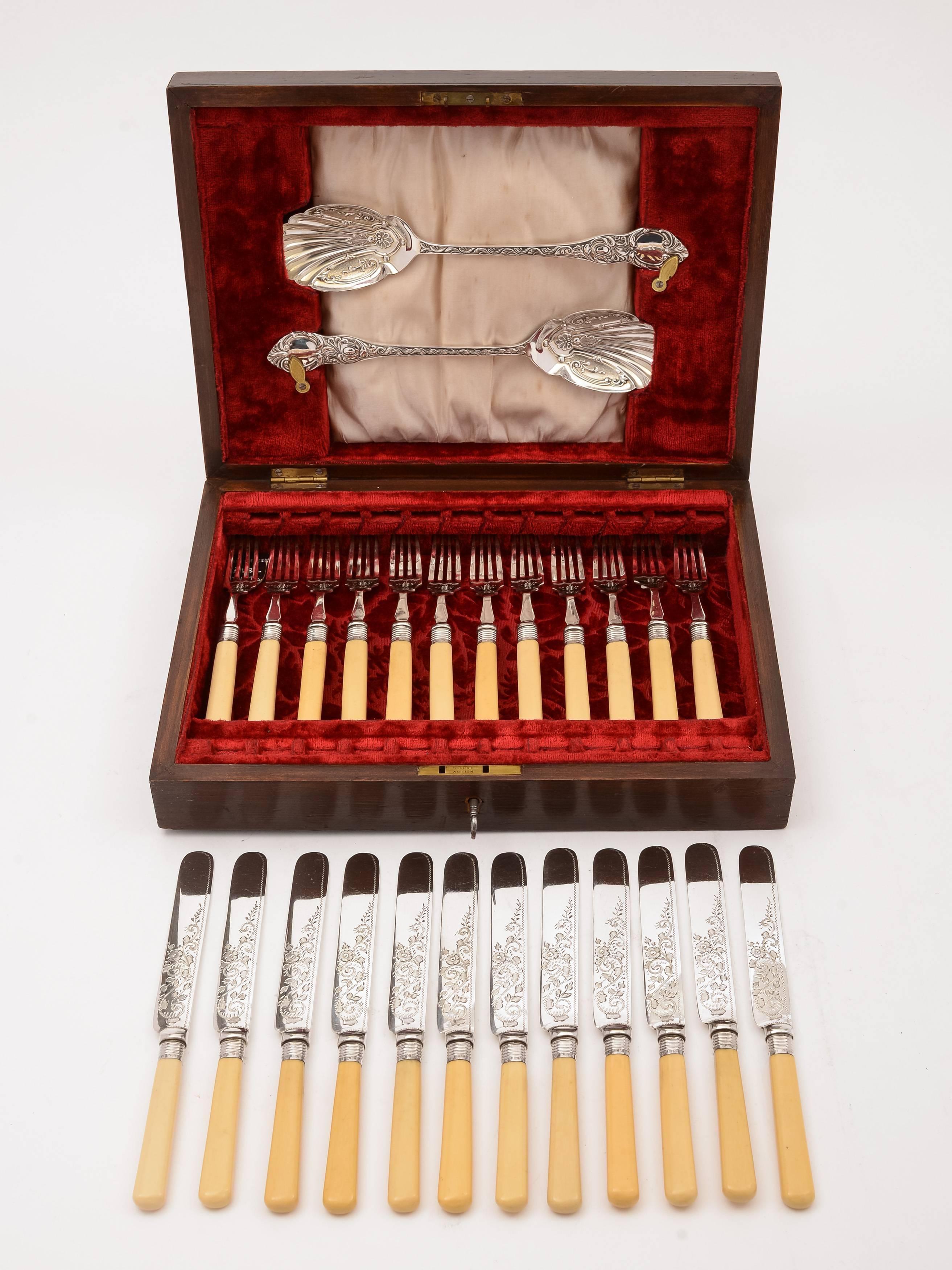 A wonderful English Edwardian cased silver plated 12 + 12 dessert set with two silver plated fruit serving spoons. The knives have lovely engraved foliate decoration with hard plastic handles and silver ferules which are hallmarked Sheffield 1904.