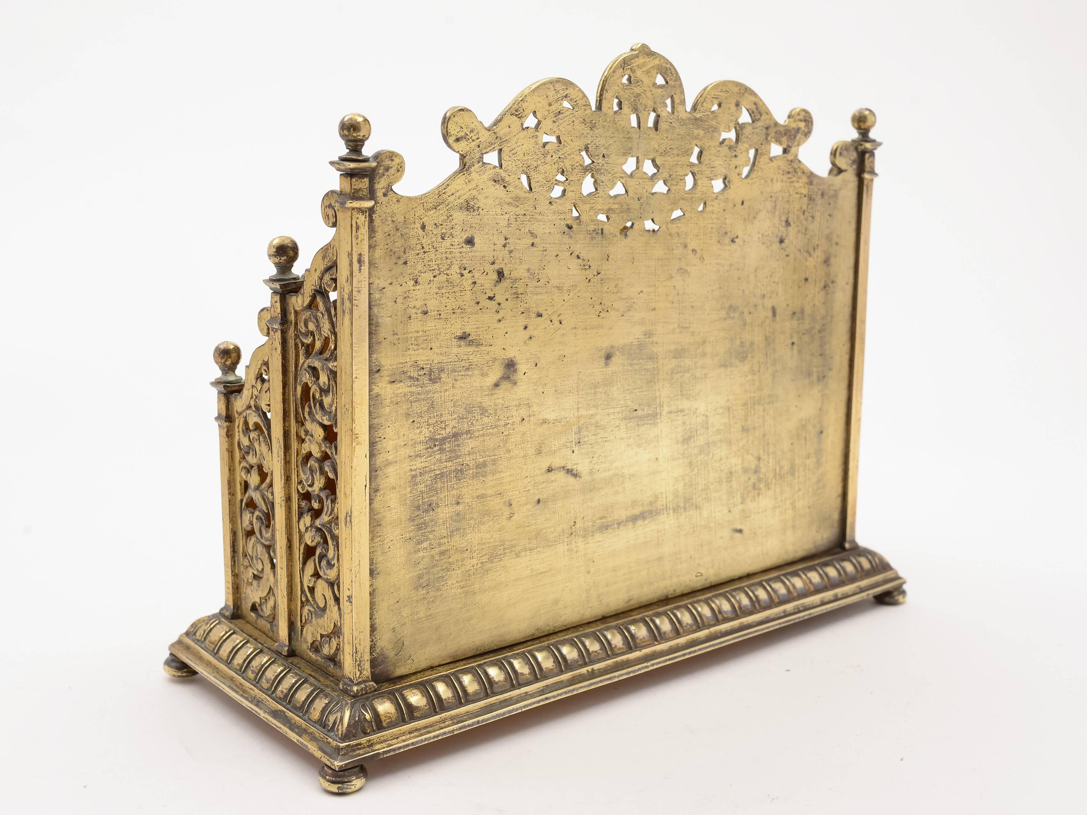 A stunning English Victorian brass letter rack with two compartments. Stands on 4 bun feet and has lovely pierced and embossed decoration, circa 1890.

Measurements: 
Height: 8
