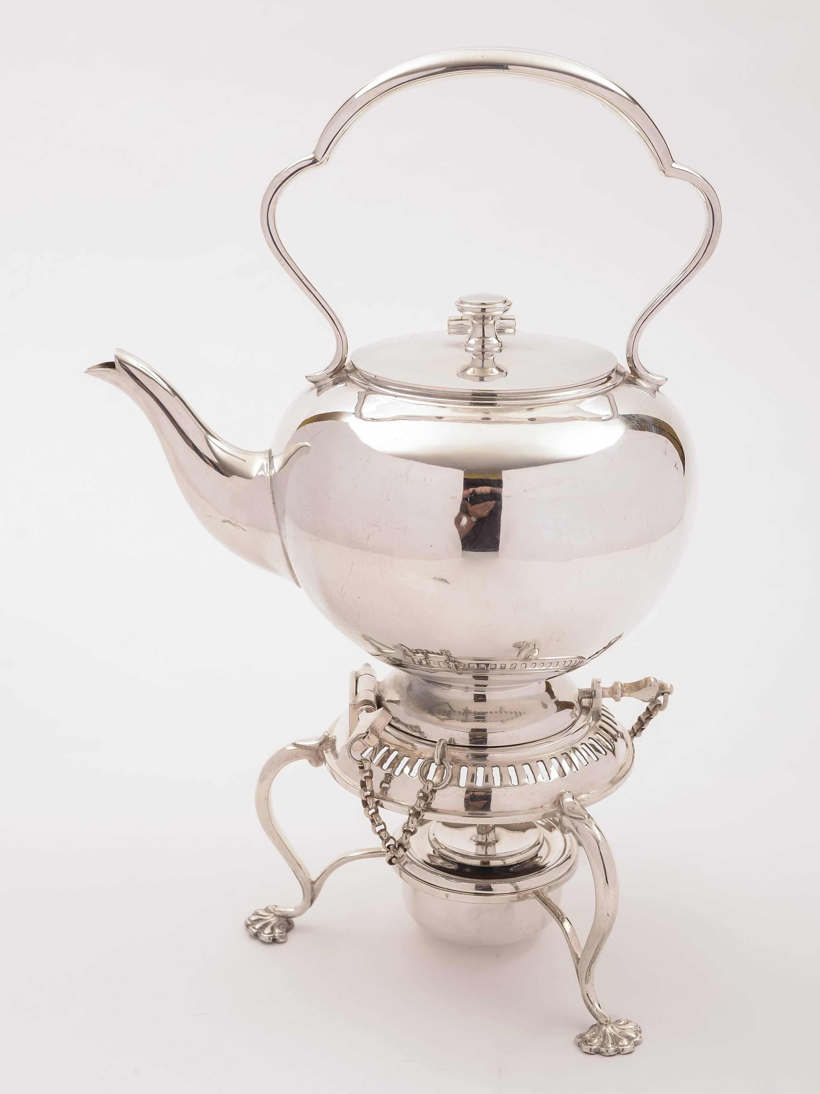 A lovely English Edwardian silver plated bachelors tea kettle. Sits on base which has three pad feet and central burner. Keys are located on base to hold the kettle in place and allow it to tip for pouring. The kettle itself is spherical and has a