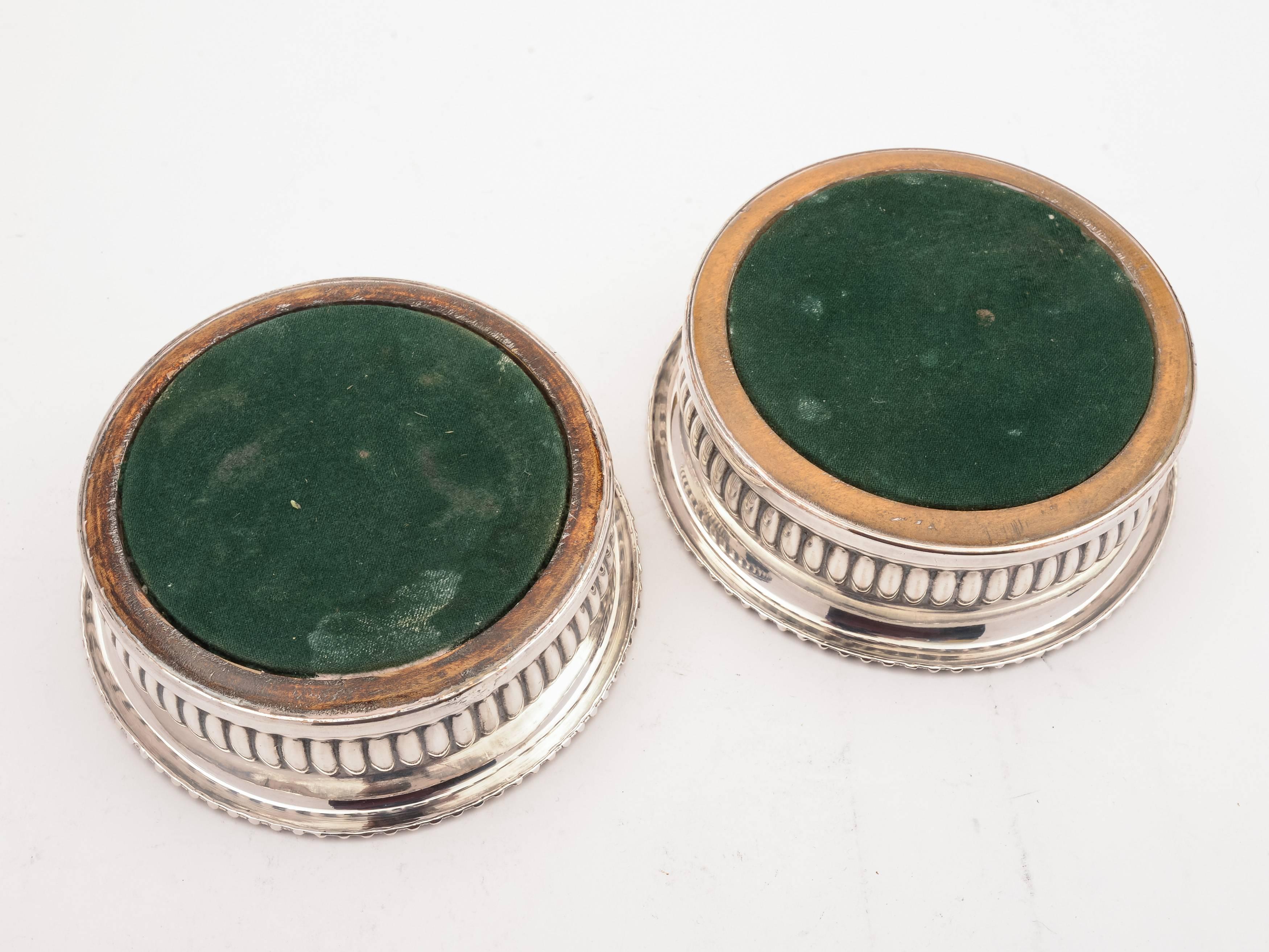 A good pair of English Victorian Sheffield plated coasters with embossed gadrooned decoration and hardwood bases with engine turned decoration, central silver plated buttons which have engraved stag family crests and felted bases. circa