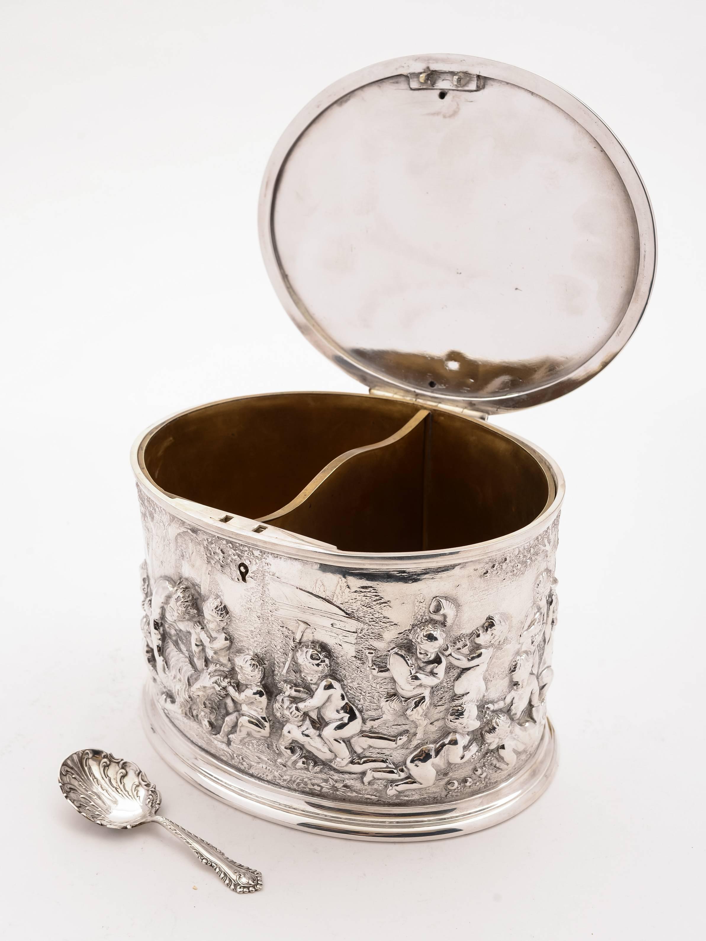 A grand English Victorian silver plated tea caddy with embossed cherub decoration and flip up lid which opens to reveal two interior compartments. The box is unmarked but is superb quality. Comes with embossed caddy spoon, circa