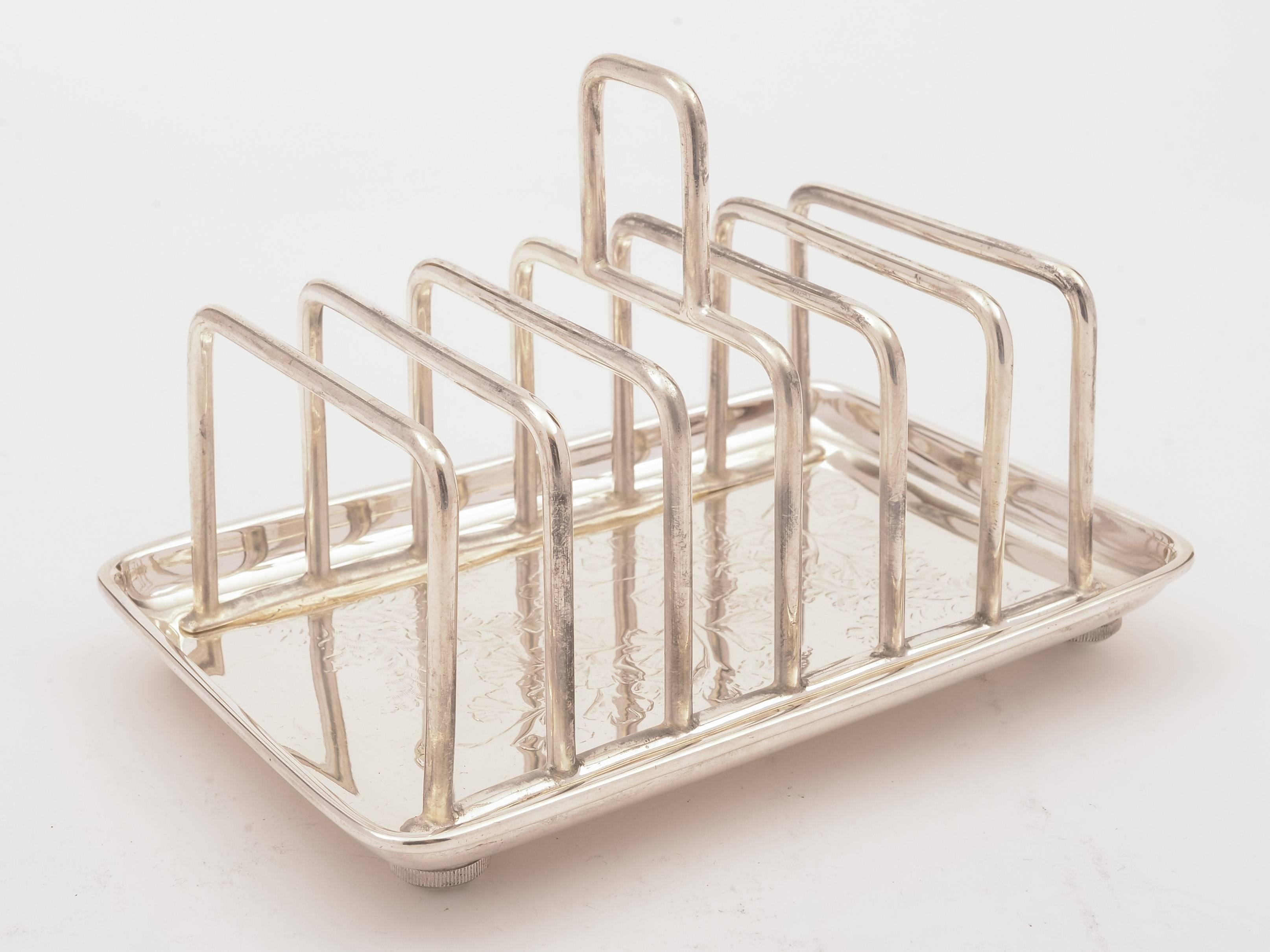 A lovely English Victorian silver plated, tray-based toast rack with 6 compartments engraved floral decoration to base, 4 bun feet and central carrying handle. Has diamond registration mark for May 1881 and marked 'C.E.N' for the maker Charles