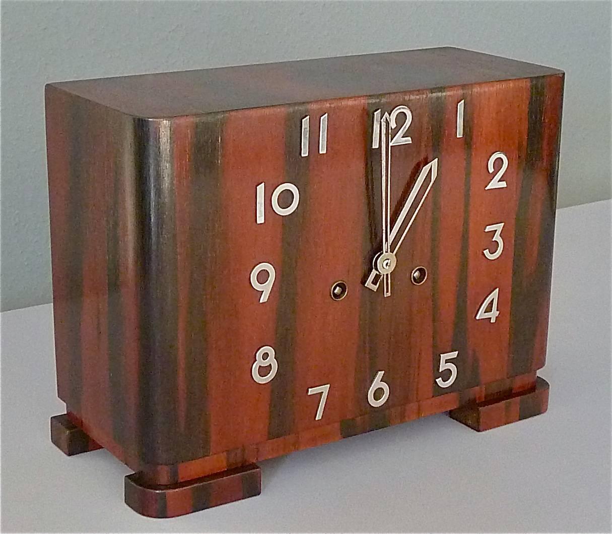 Awesome Art Deco / Bauhaus mantel desk clock made in Germany, circa 1925-1935 with attribution to Kienzle or Junghans in Germany. It is made of dark wood on a wood body with chromed numbers and hands. The modernist clock has a mechanic movement with