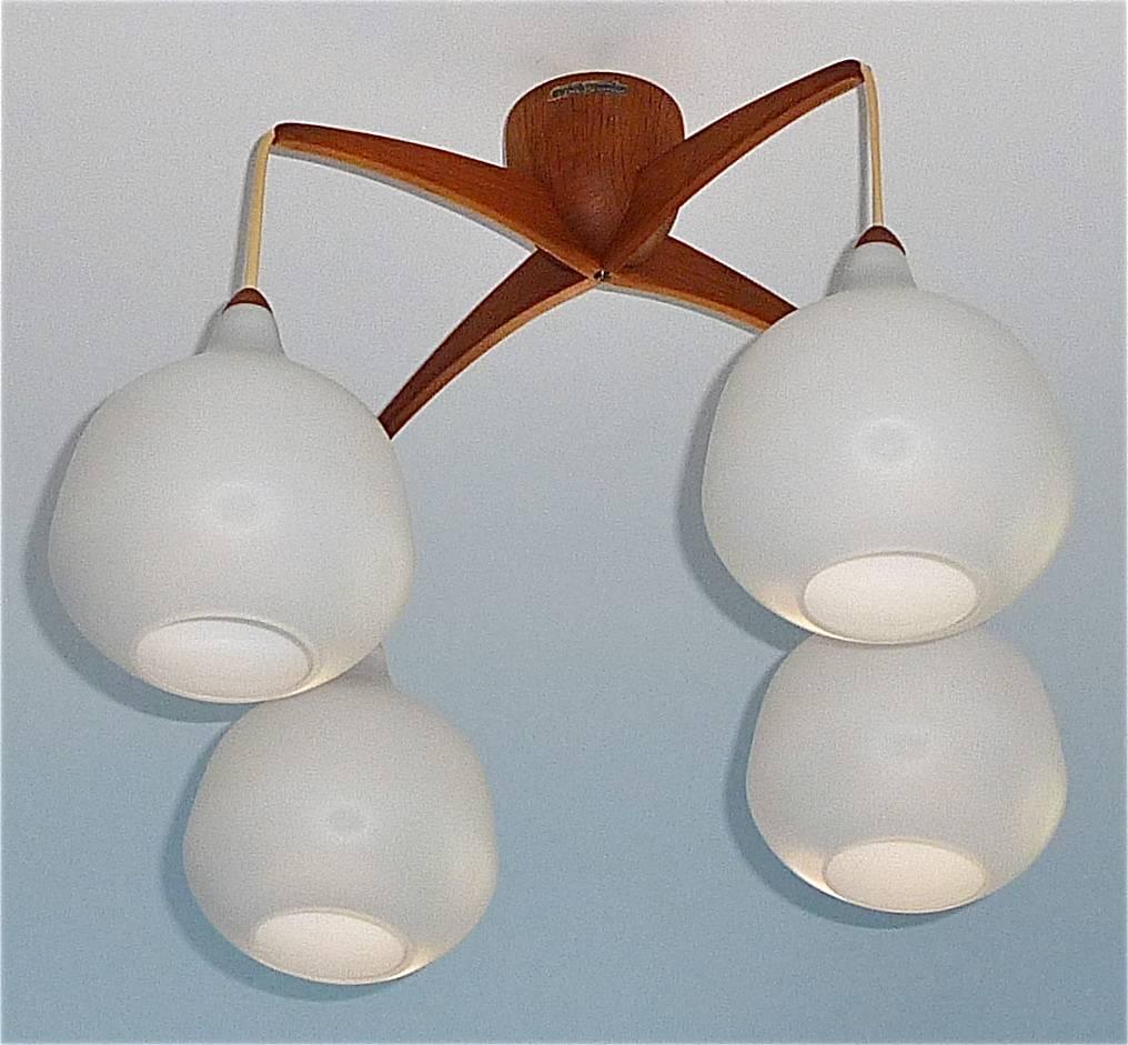 Sculptural and rare Midcentury Scandinavian ceiling / pendant teak lamp designed by Uno & Östen Kristiansson, circa 1960 and manufactured by Luxus Vittsjö, Sweden. The gorgeous four-arm teak chandelier has opaque white drop-shape glass shades with a