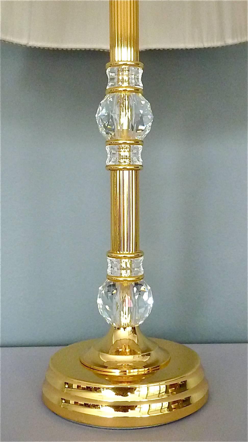 Fine and noble table lamp made by Palwa, Germany, circa 1970. It has a gilt brass metal base and stem with big beautifully hand-cut and polished facetted crystal glass ball insets which sparkle like diamonds, on top a very expensive, classy and