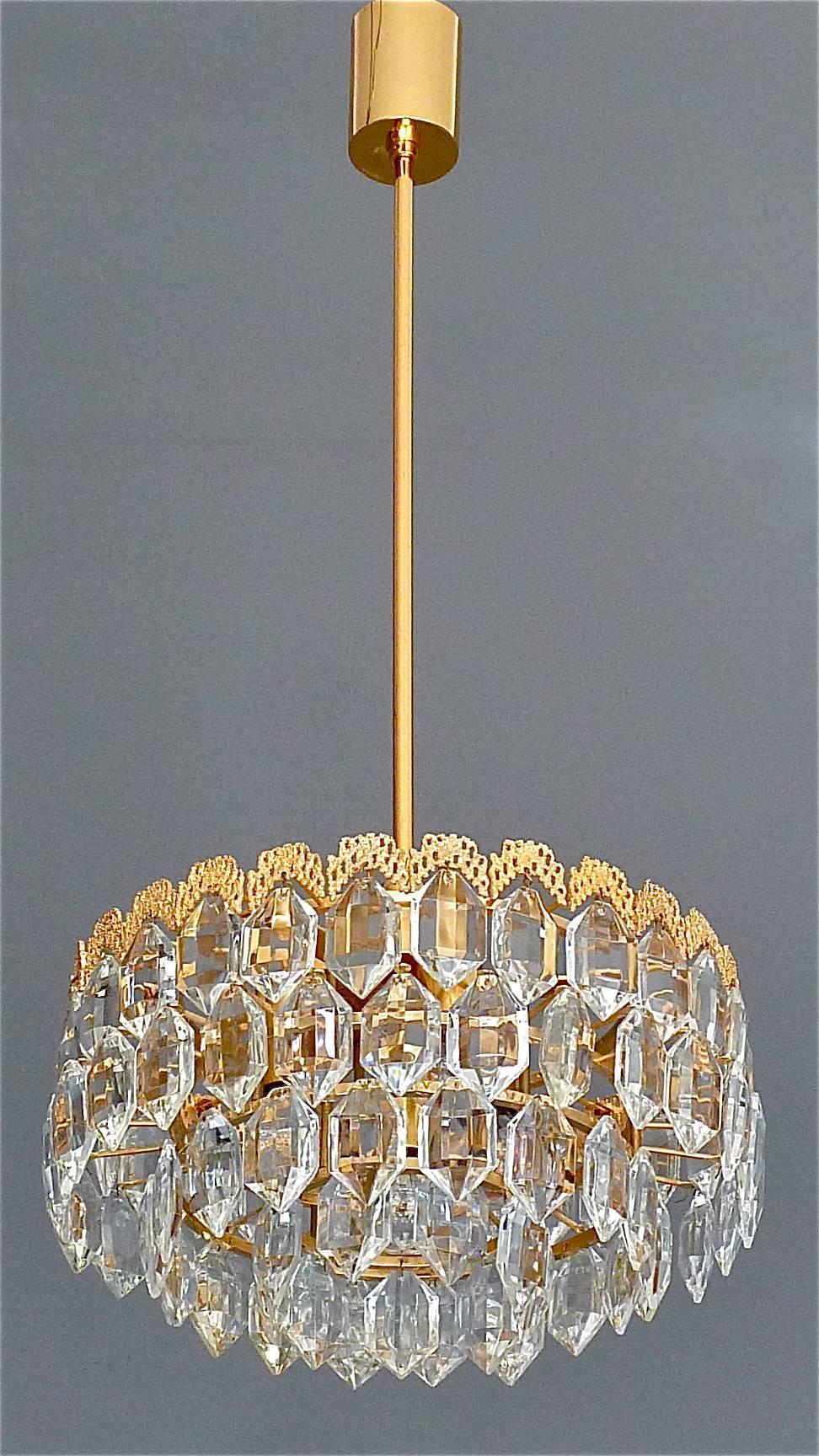 Precious gilt brass and crystal glass chandelier made by the famous company Bakalowits, Austria circa 1960s. The ceiling fixture and the frame are made of gilt brass with a wonderful gilt decoration on top of the upper frame which looks like a