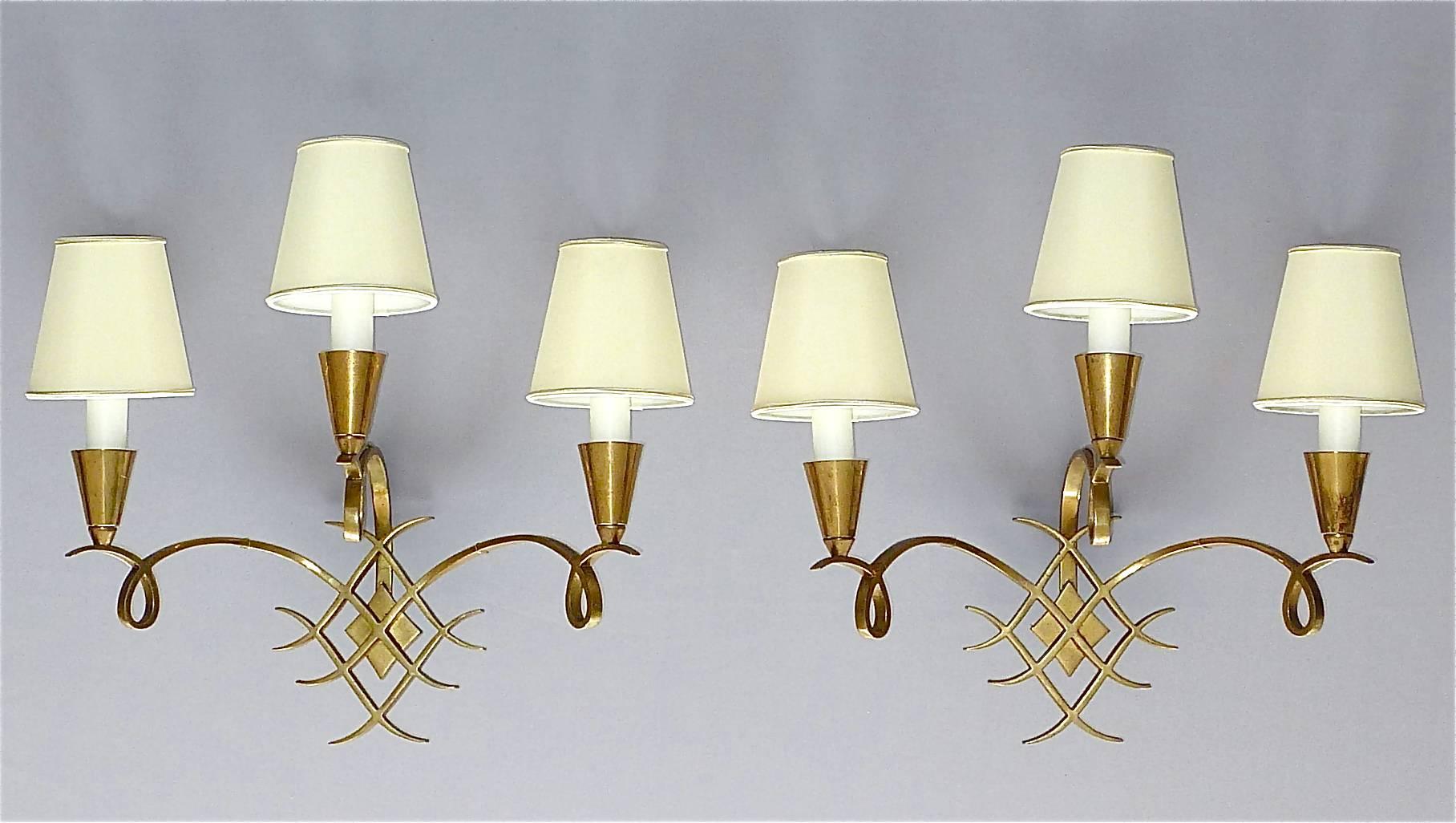 Elegant and large pair of French Art Deco bronze wall lights or sconces by Jules Leleu, France, circa 1935-1945. Each lamp is made of bronze and has three scrolled arms. They are newly rewired and the French fitting is replaced. They are in fine