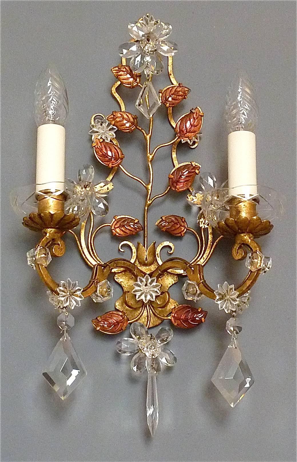 Refined pair of floral golden Maison Baguès Style leaf sconces, France circa 1950. They are made of gilt iron / metal and faceted crystal glass with sparkling glass beads forming amazing flowers and leaves. The beautiful two-light lamps stay in a