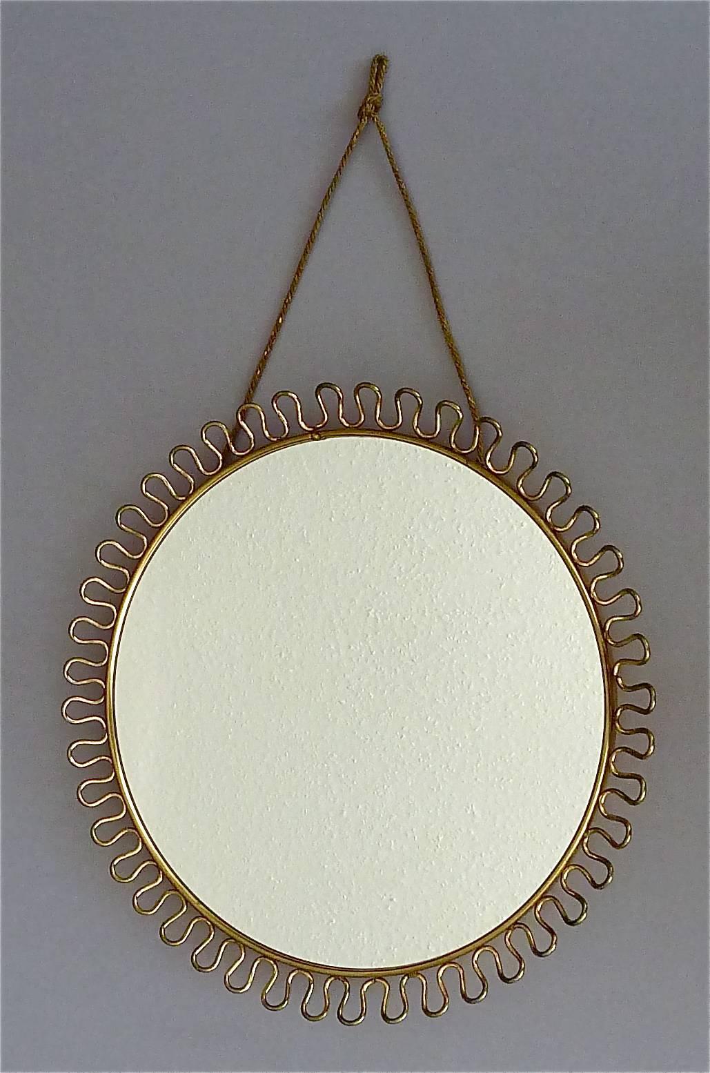 Sculptural and elegant pair of midcentury round wall mirrors by Josef Frank Austria / Sweden for Svenskt Tenn, circa 1940-1950 which are made of brass, black enameled metal and a beautiful brass loop-wire-decoration. One of the mirrors has still its