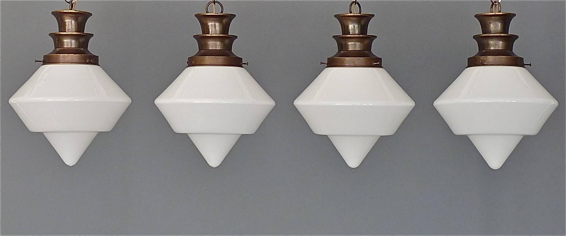 A rare set of four Art Deco / Bauhaus ceiling lights or flush mounts, French or German, circa 1930. The newly rewired pendant lamps are made of patinated brass metal and opaque white glass. They take one E27 standard screw bulbs each to illuminate.