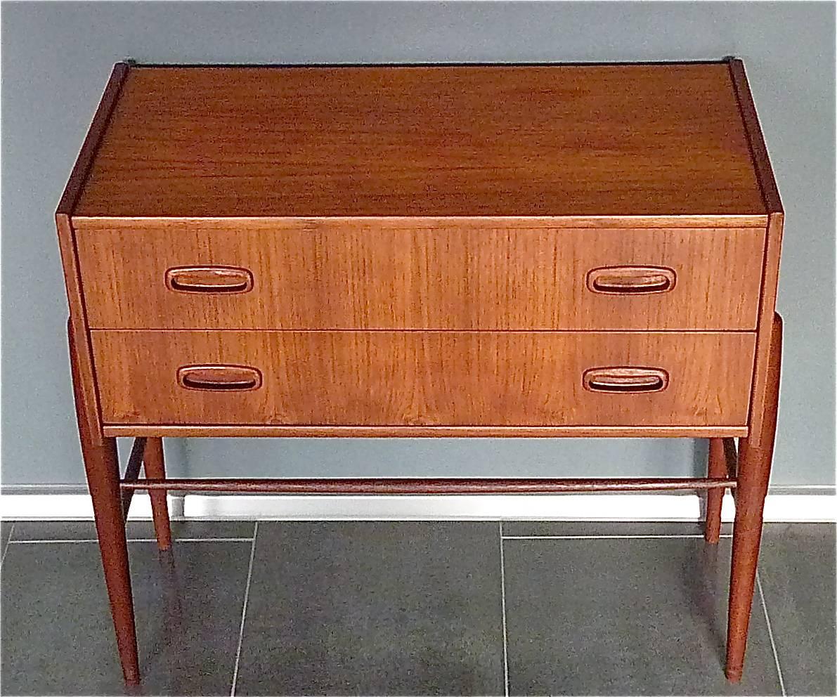 Elegant and beautiful small Danish teak wooden chest of drawers or cabinet designed and executed in Denmark in the late 1950s-early 1960s. The case, with two drawers with very nice solid teak wooden handles, is made of teak veneer wood which rests