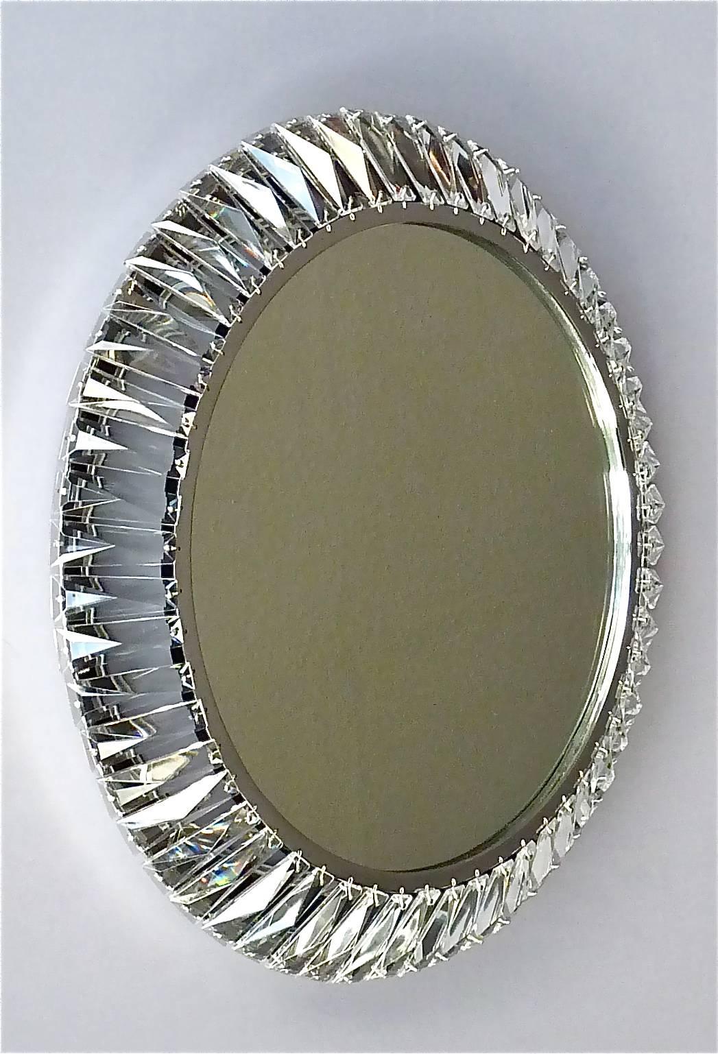 Round signed chrome brass metal faceted crystal glass backlit wall mirror made by Palwa, Germany, circa 1960-1970, documented in the Palwa sales catalog. The frame has lots of beautiful hand-cut faceted and polished crystals in the shape of a