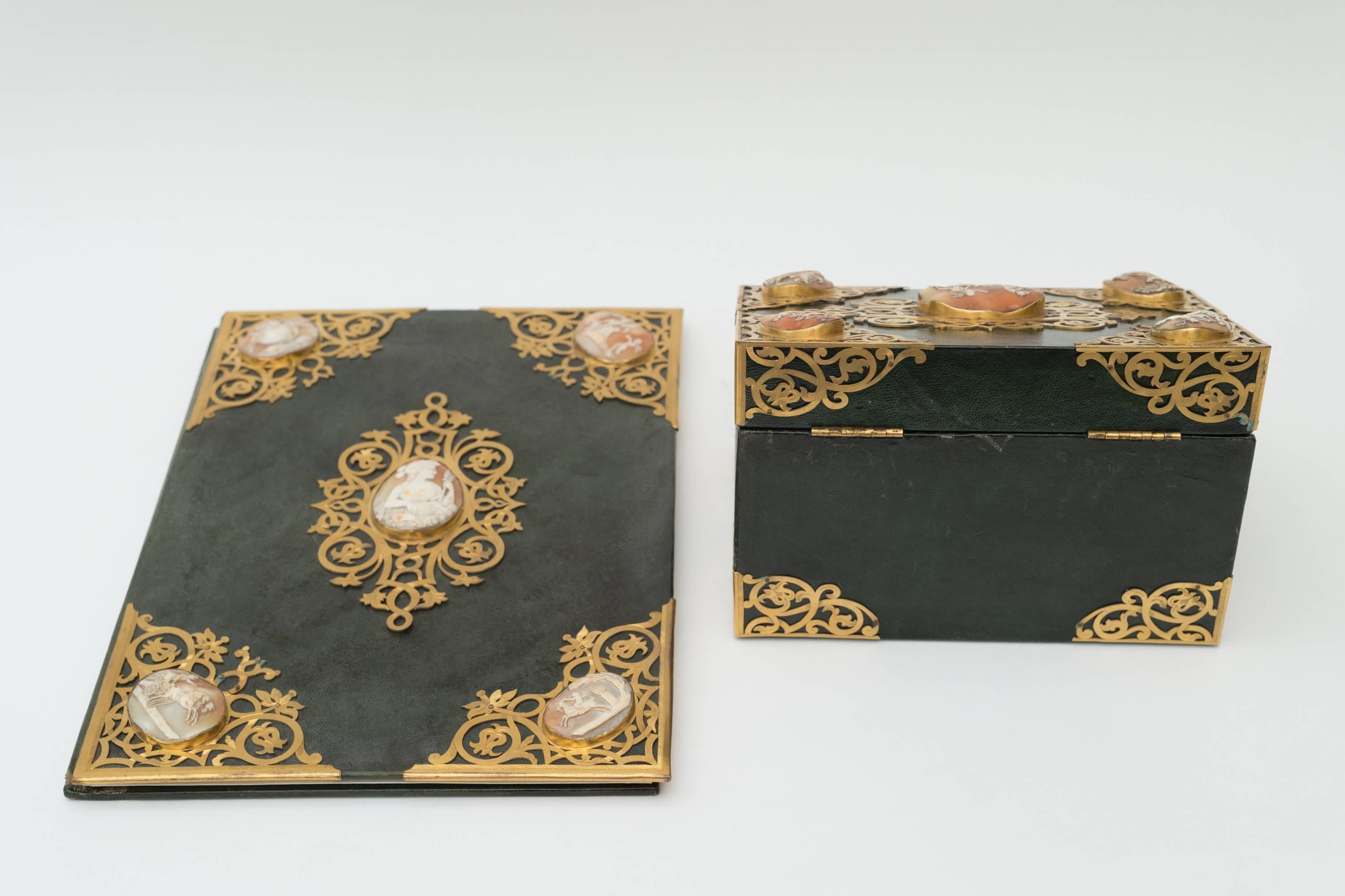 A Victoria green leather bound writing box and blotter
Each with five mounted cameos mounted within gilded borders and centrepieces 

Measures: Blotter width 25cm, length 35.75cm, depth 3 cm 
Writing box width 22 cm, depth 15 cm, height 16.5