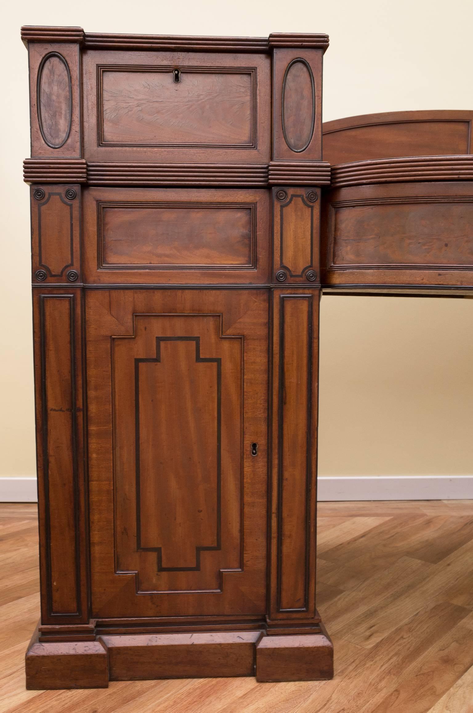 A large George III mahogany twin pedestal sideboard with inlaid ebony stringing.
There are two large central draws and two smaller draws above cupboards, one of which houses a wine rack. 

There is evidence that at one time it may have stood on