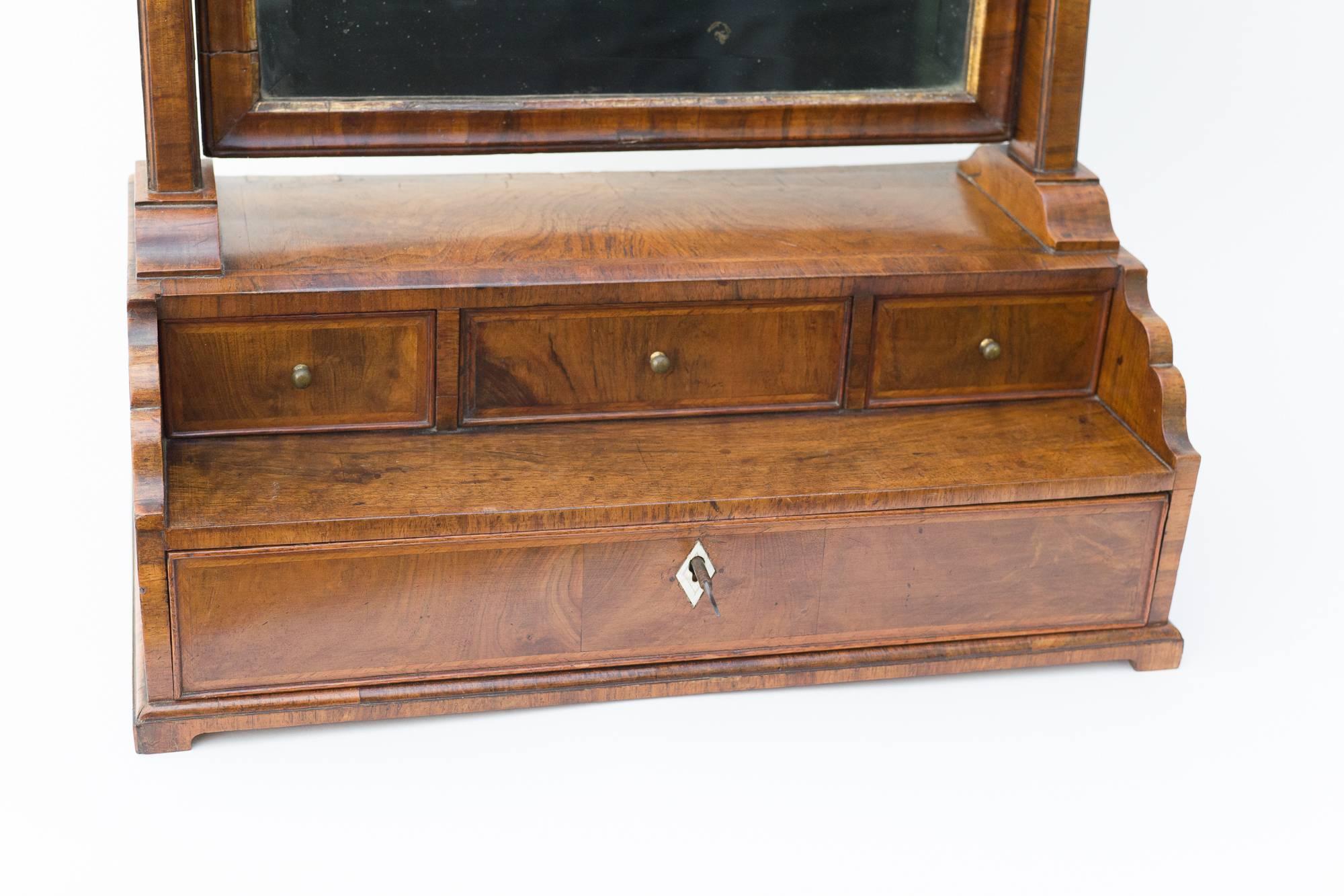 George II walnut dressing table mirror with bevelled glass.

Three small oak lined draws above a larger single full width draw.



  