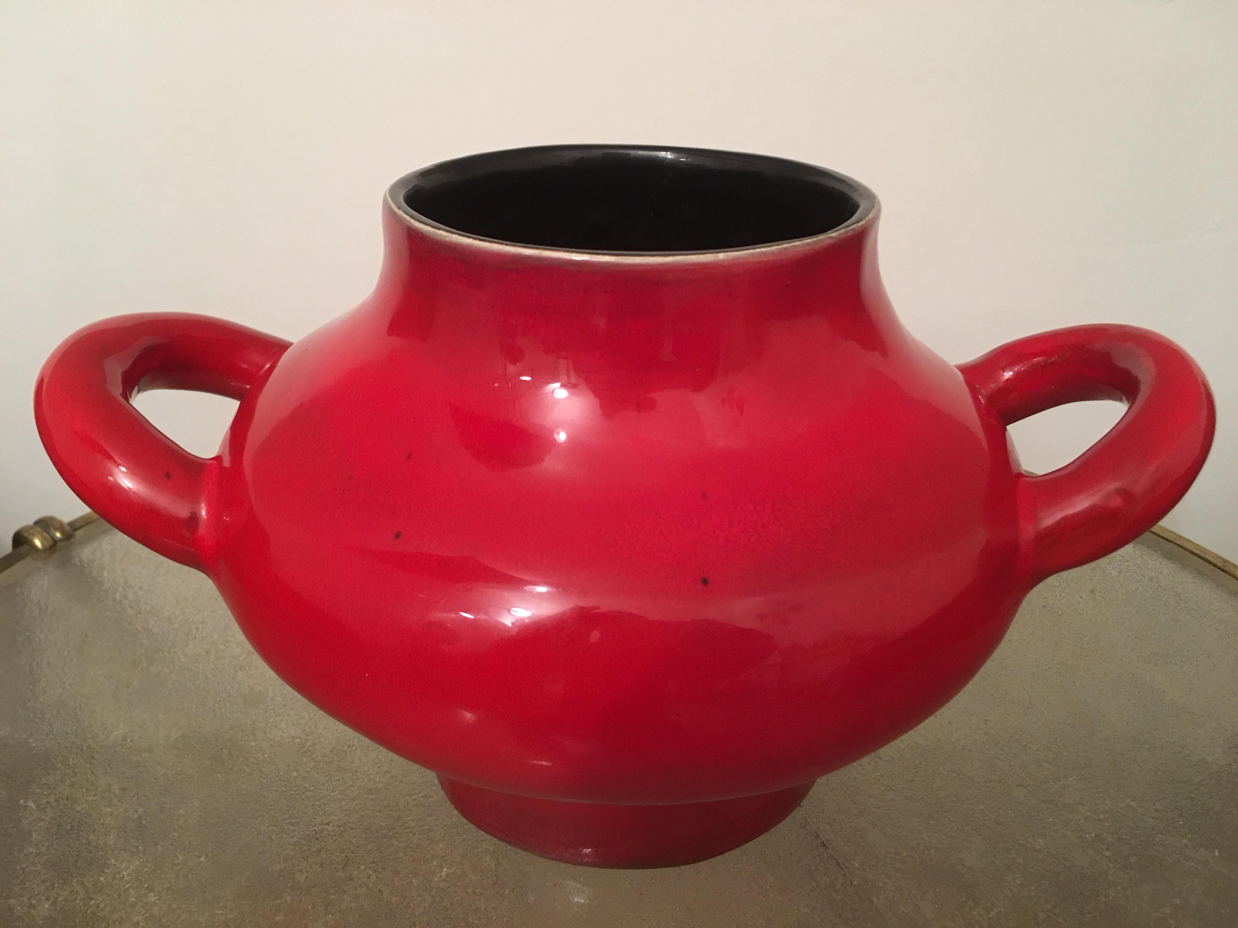Large ceramic vase or jar with handles attributed to Georges Jouve in 1950s.
Beautiful red and black colors that highlight the original form of this piece.
We find this same red glaze with some black dots on vases rolls and a chalice vase of 1955