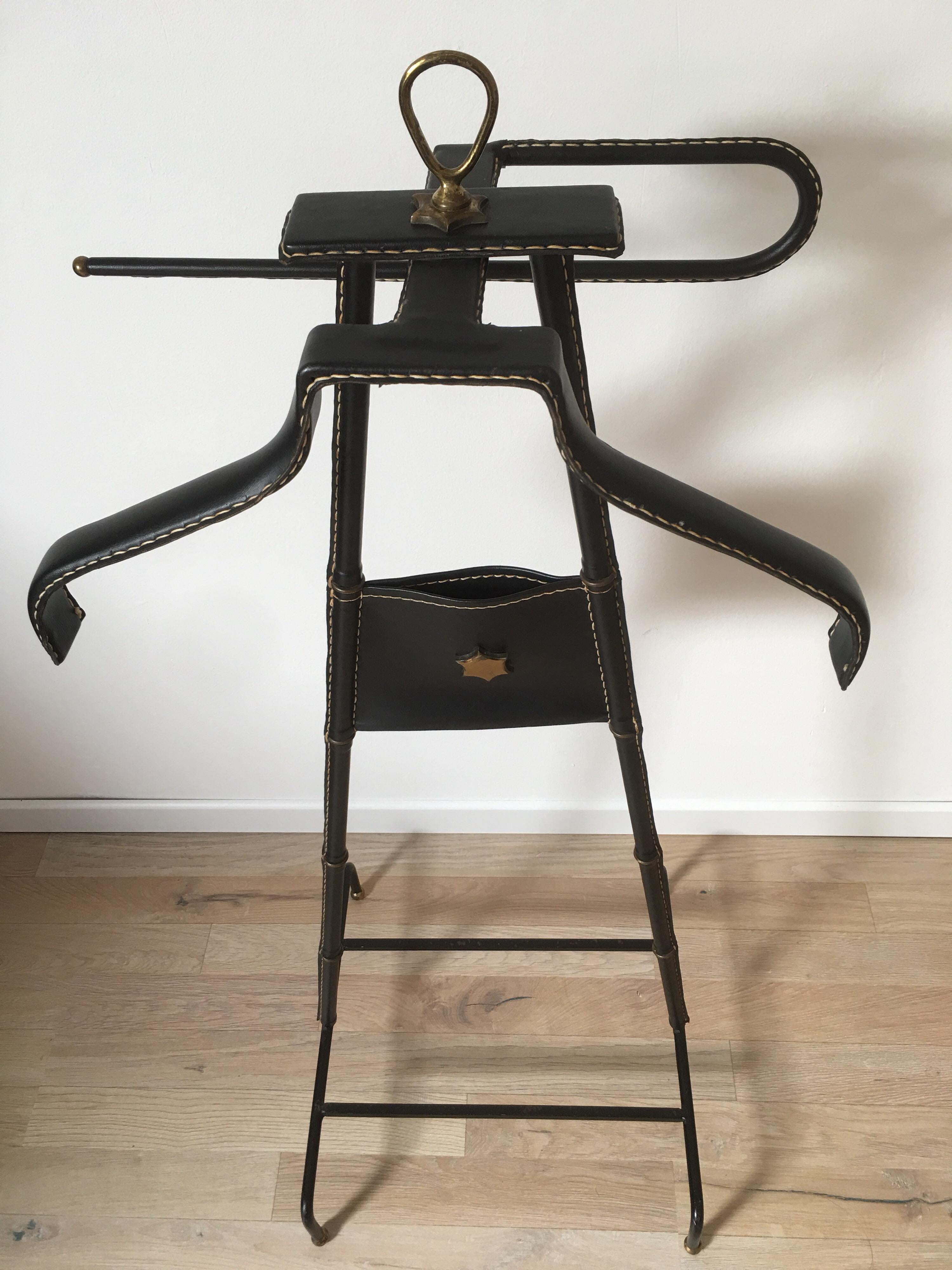 Beautiful black stitched leather valet designed by Jacques Adnet in France in 1950s.
This rare model of valet de nuit, fully leather-wrapped, has 2 arms to wear shirts and pants. It rests on a bamboo-shaped base, brass rings and saddle-stitched