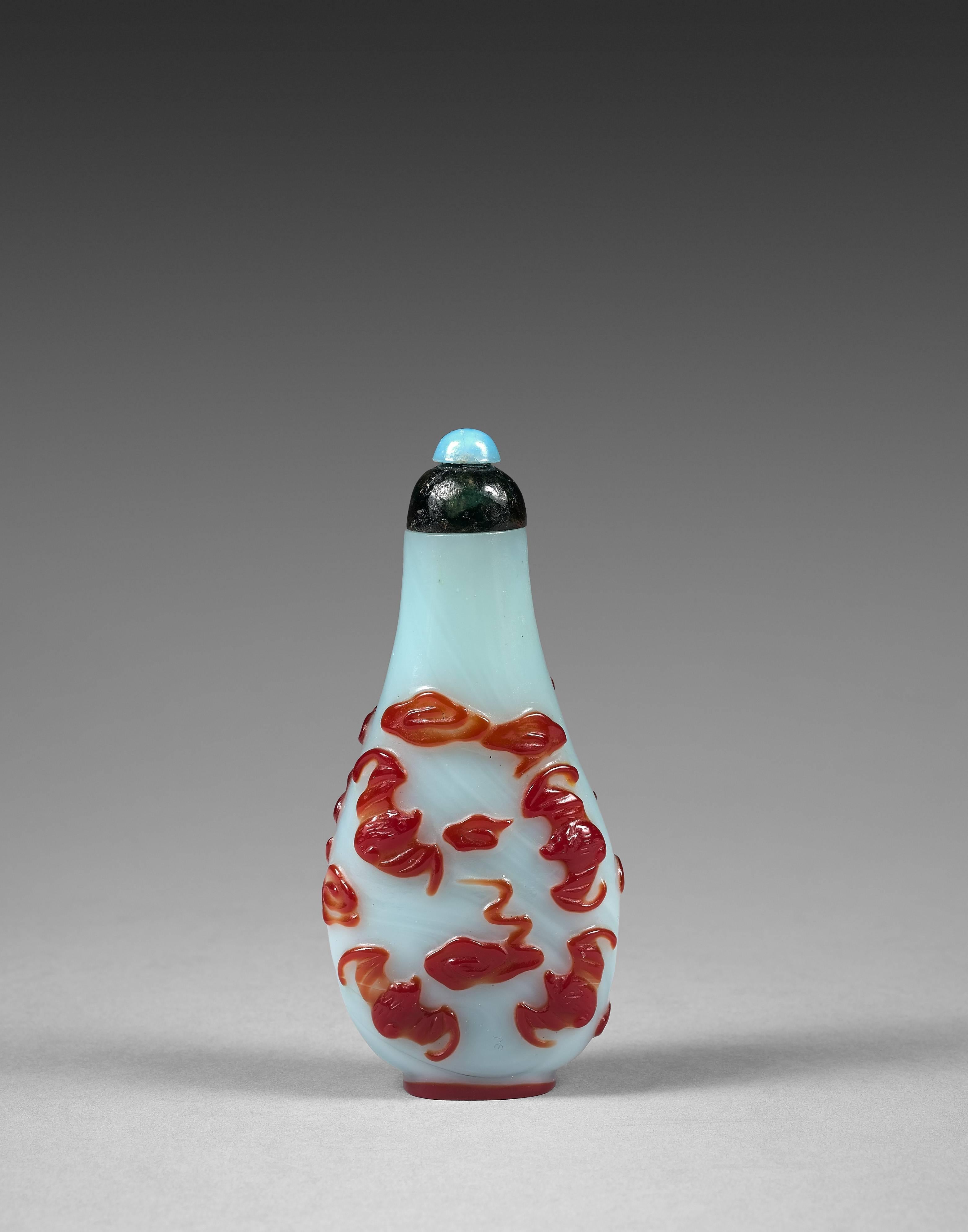 The snuffbottle with an elongated body, surmounted by a high collar ending in a small two-tone cap. The body decorated with bats flying among the clouds in red overlay glass.

Provenance: Private French collection.