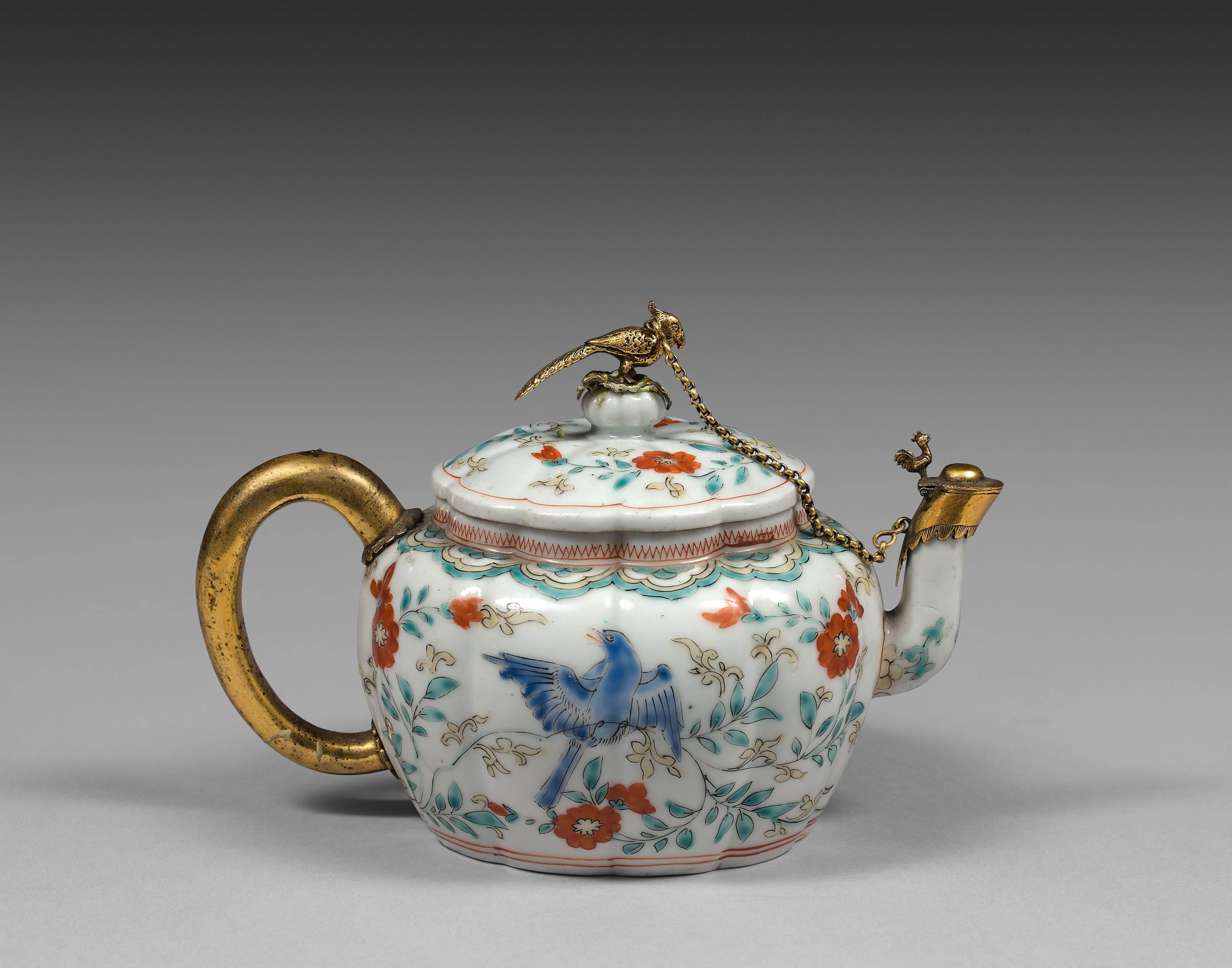 The Kakiemon porcelain lobed oval teapot with matching lid. The teapot decorated with birds among flowers in red-orange, blue, yellow, turquoise overglaze enamels. The teapot and lid enhanced by 17th century Dutch Fine silver-gilt mounts and handle.