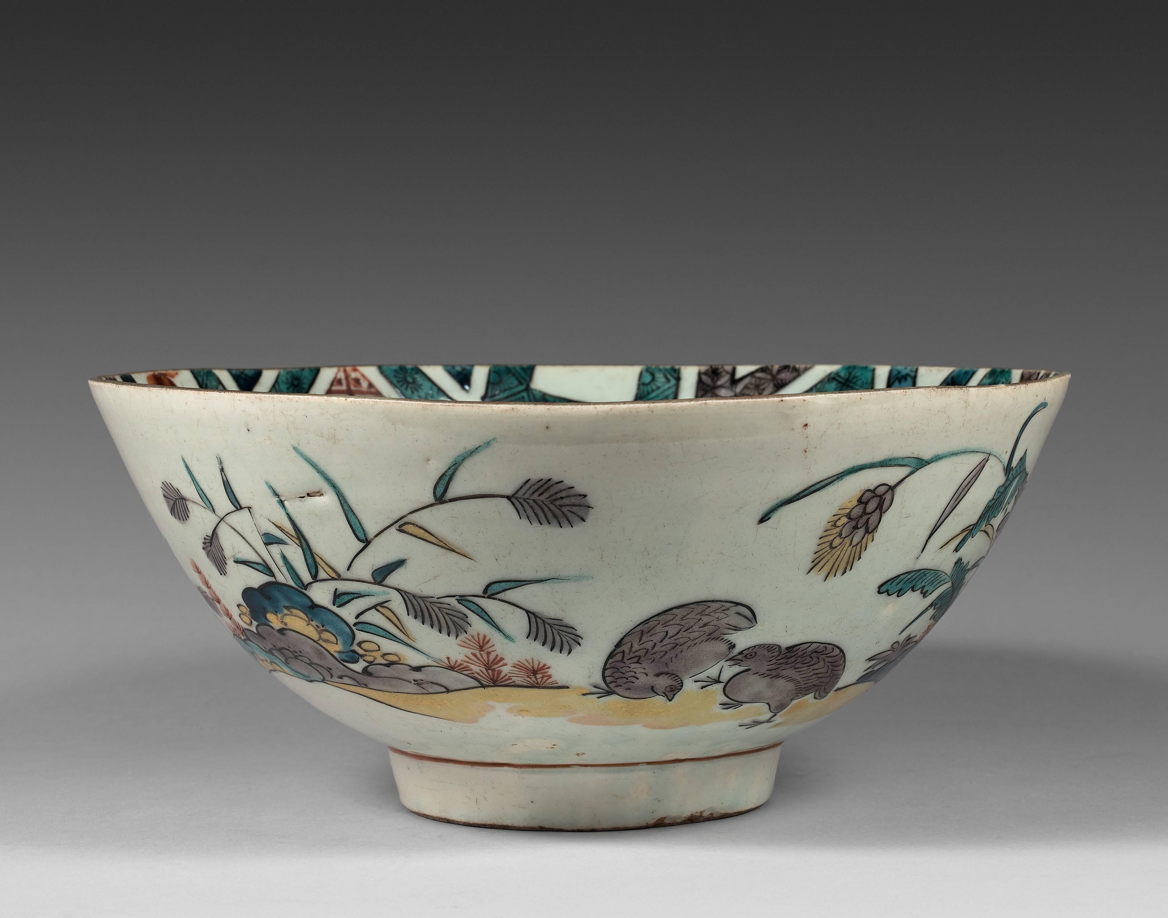 The bowl with a slightly rounded body resting on a short cylindrical foot. The inside with a decor of phoenix and cherry blossoms in diamonds with cash coins ground. The outside with quails among the millets. The base with Fuku mark in black and