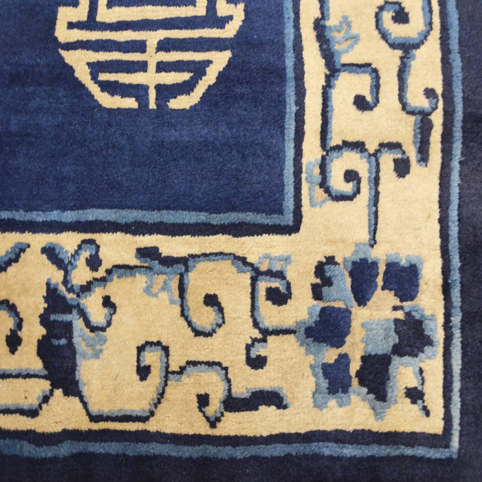 China Beijing carpet with characteristic bat design throughout the central field on a typical blue background of this type of pieces.