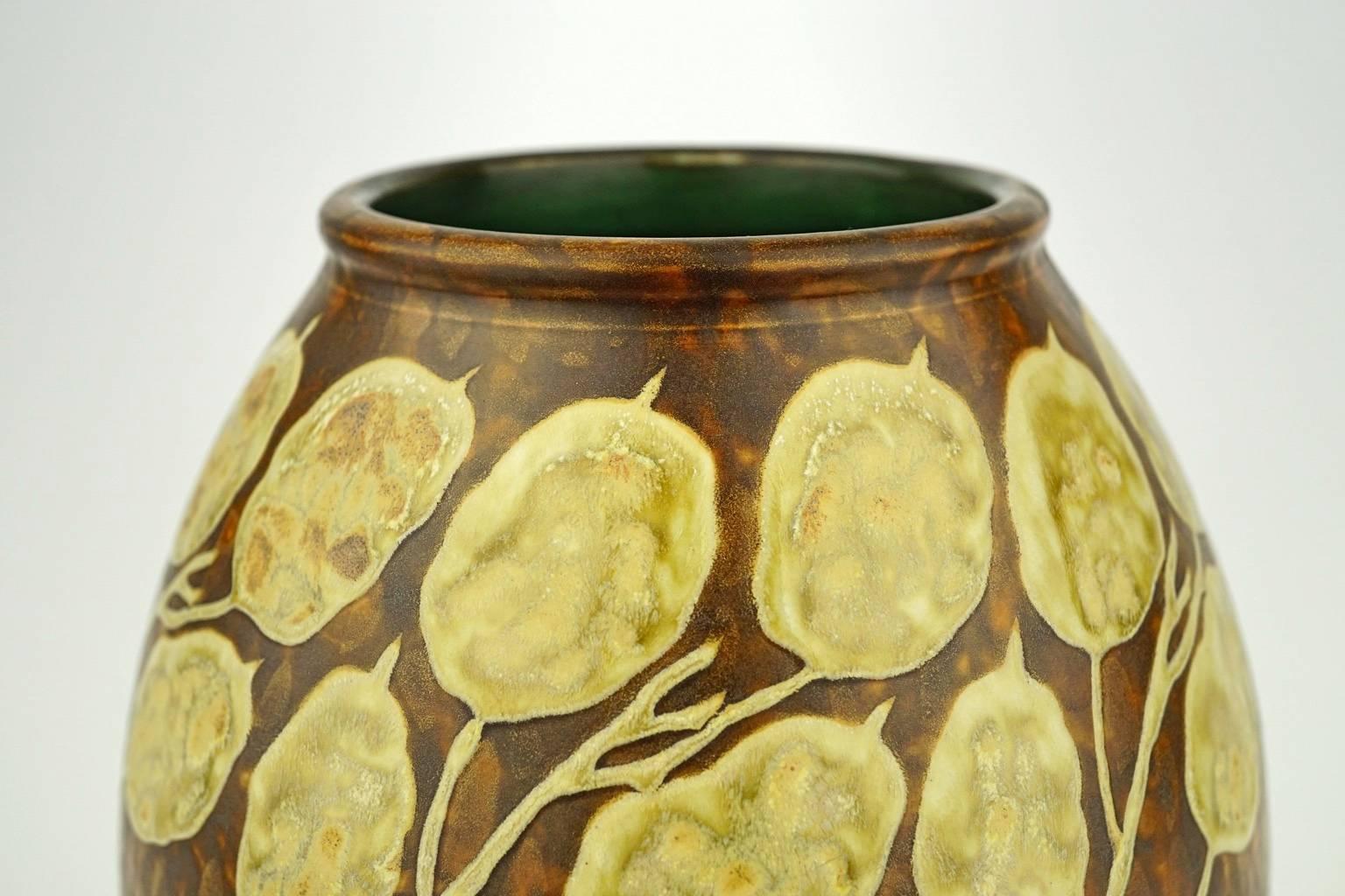 This Art Deco matte stoneware vase has a dried honesty design on gold background in gradation of brown and green. Marks: D 659. F 900.

Size: H 18 cm, Diameter base 11.2 cm, Diameter top 9.9 cm.