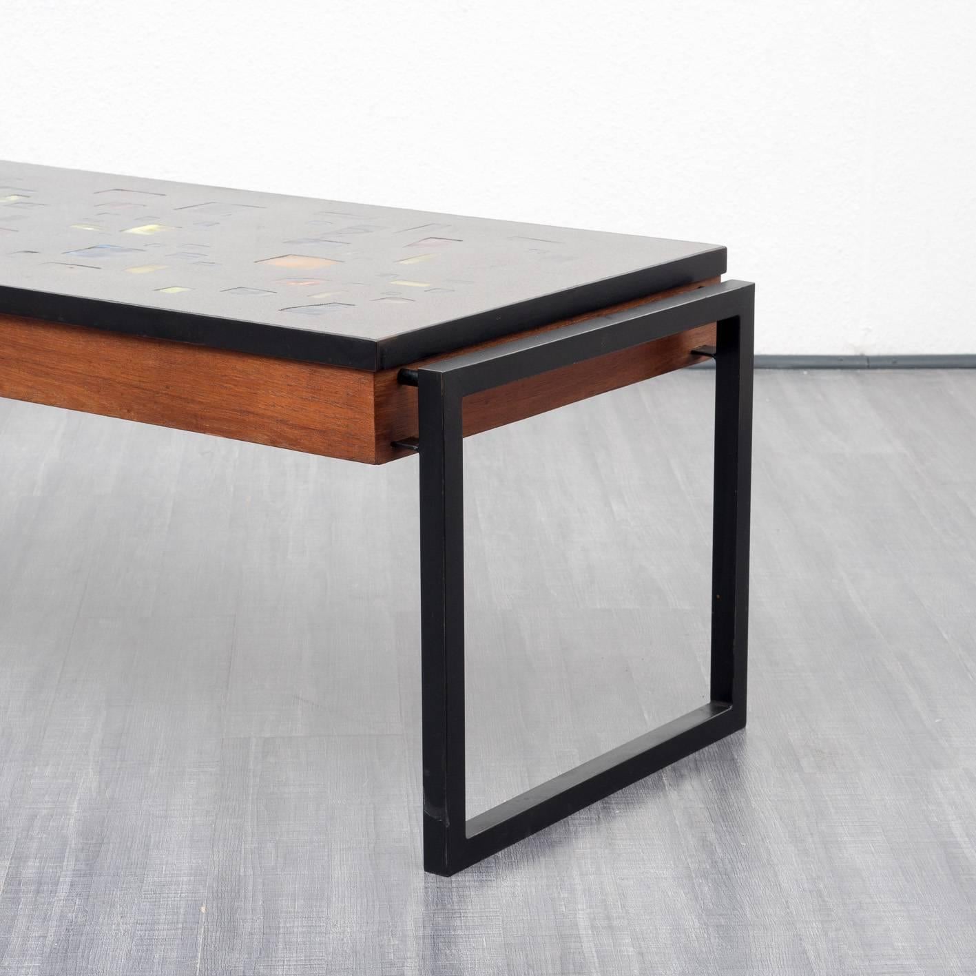 Extraordinary coffee table from the 1960s. Teak frame with black, vat-shaped square steel tube feet. The tabletop is composed of colored plastic stones, cast in artificial resin, which can be illuminated from the bottom. The light can be switched on