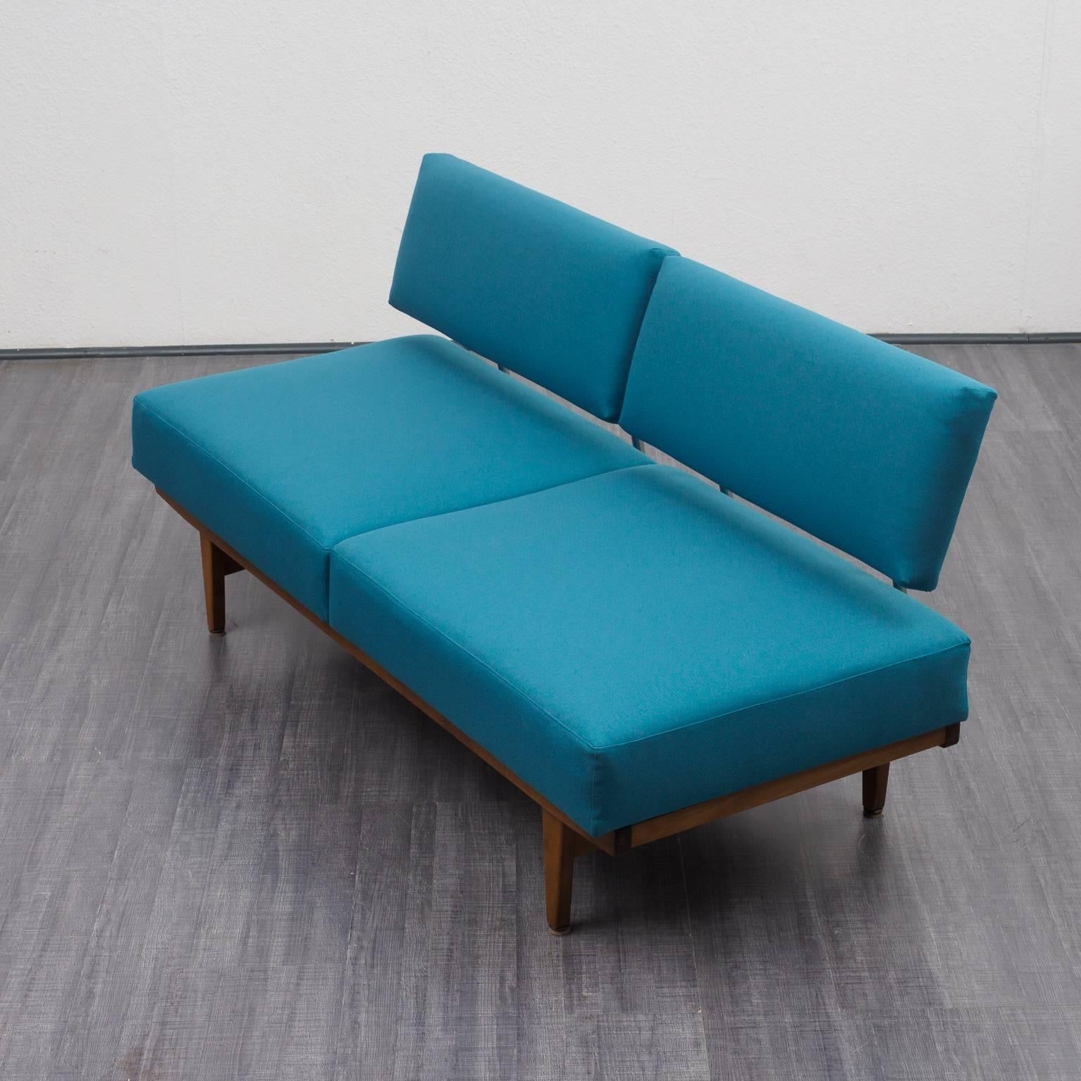 Classic 1960s daybed with solid wood frame and backrest supported by chrome-plated iron. The sofa is professionally reupholstered with new cover in high quality teal blue fabric. With a refined adjustable turning feature the sofa turns into a