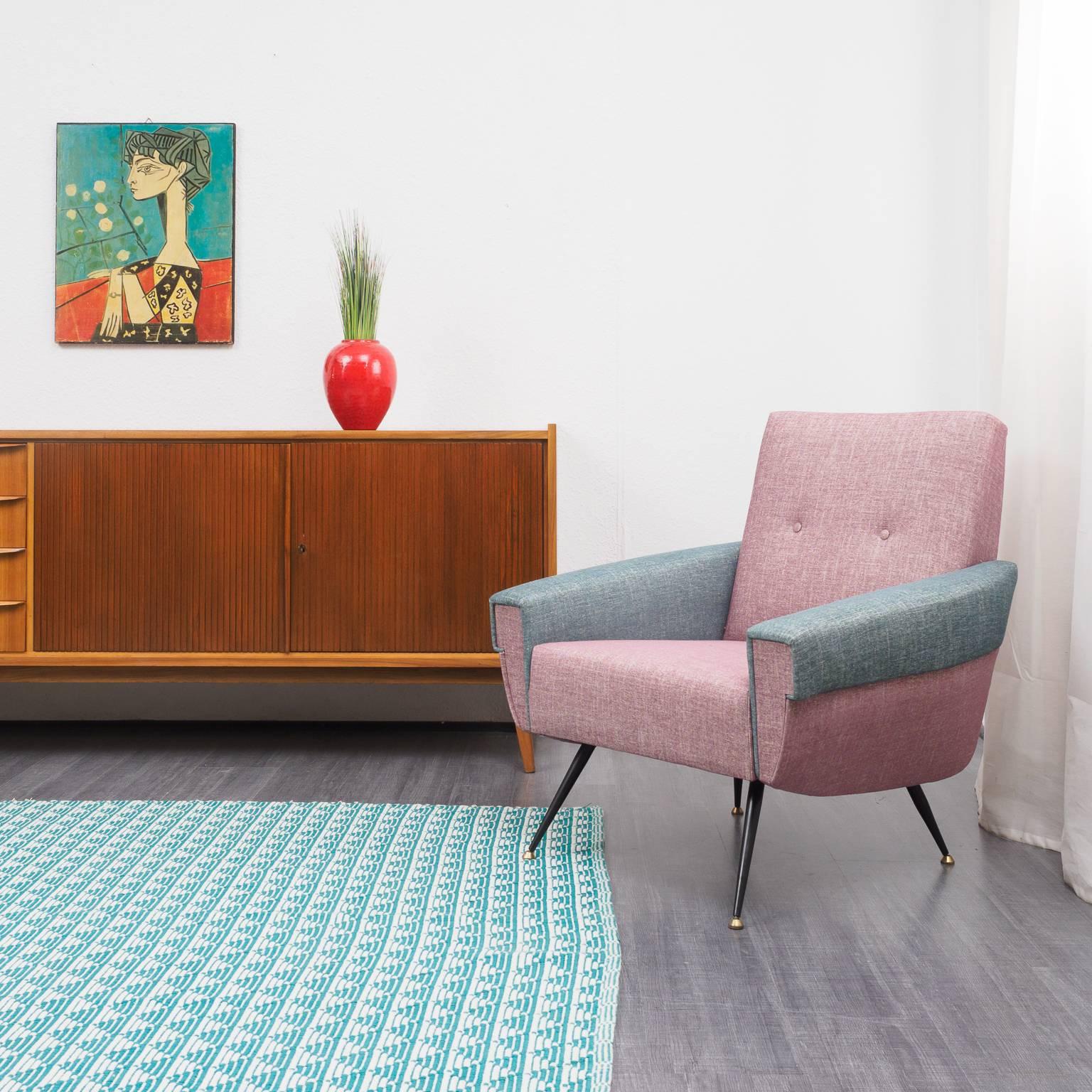 Professionally and lovingly reupholstered 1950s easy chair with new foam and high quality fabric. The elegant chair comes in the color tone rose quartz with broad armrests in teal-green. The feet are made in delicate black varnished metal with brass