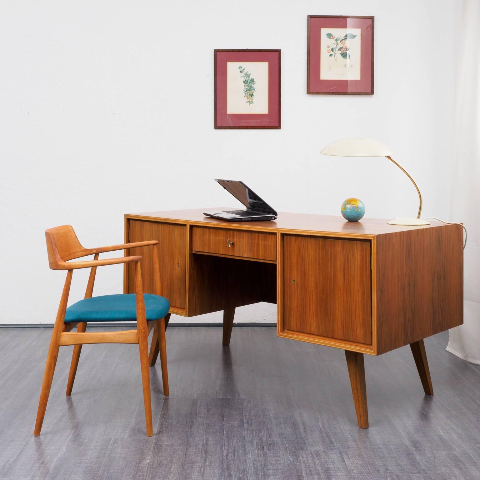 Big walnut desk from the 1960s, classic design. The desk has walnut veneer all around and comes with one lockable drawer, two lockable doors and three solid wood drawers inside. Practical book shelf at the back.

Good condition with small traces of