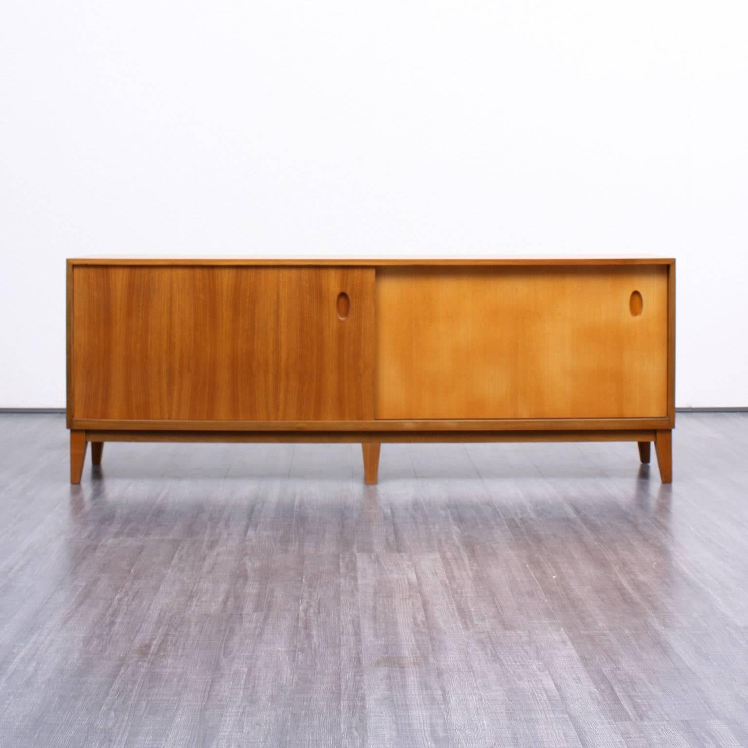 Slim sideboard from the 1950s. Design by Georg Satink for WK Möbel, 1952. Walnut veneer with bicolored sliding doors. High-quality workmanship with nice handles.

Good condition with small traces of usage.