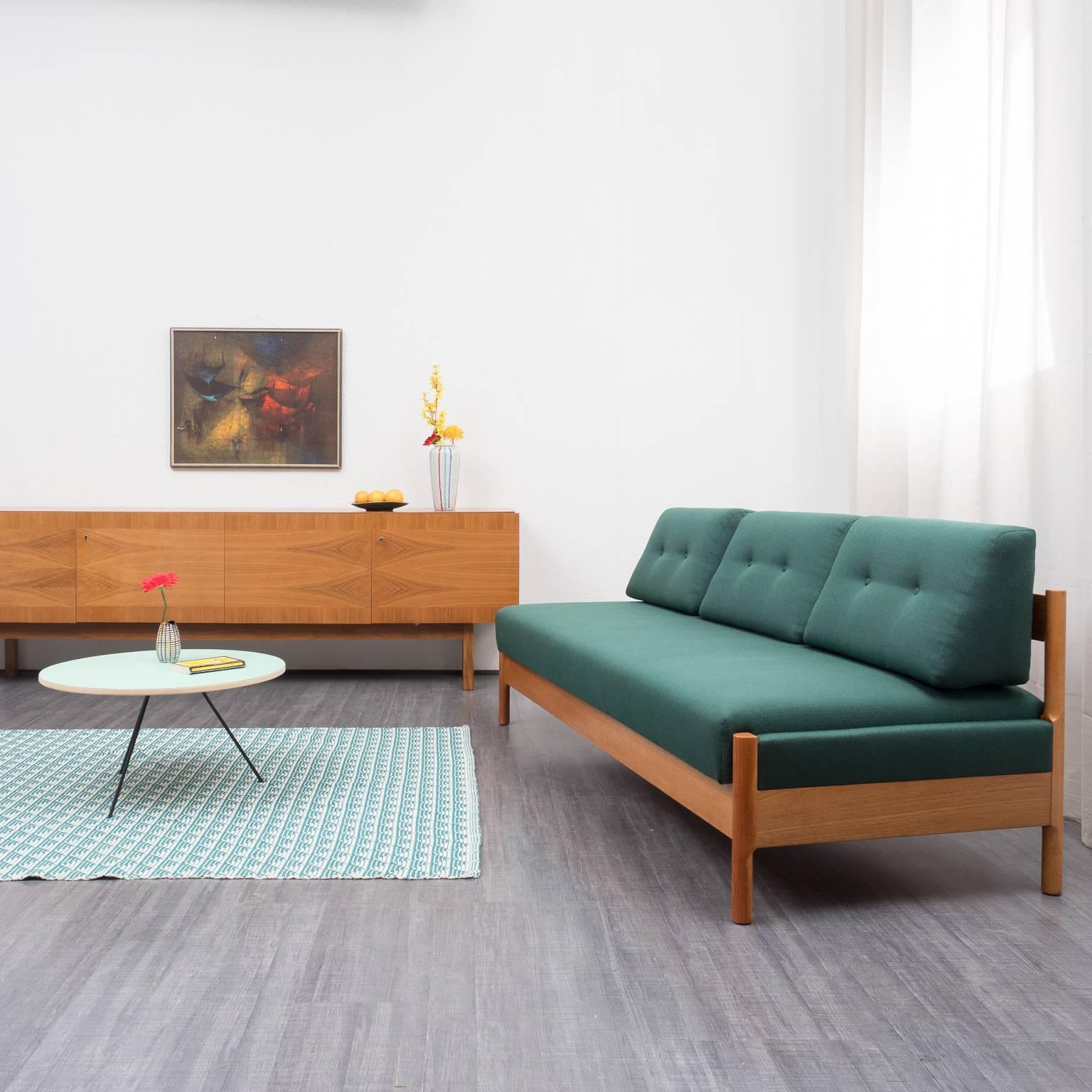 Classic daybed from the 1970s with solid teak frame. The sofa was professionally restored by the upholsterer and covered with a high-quality dark green-black mottled cushion fabric. The backrest cushions are removable, hinged mattress. Very good