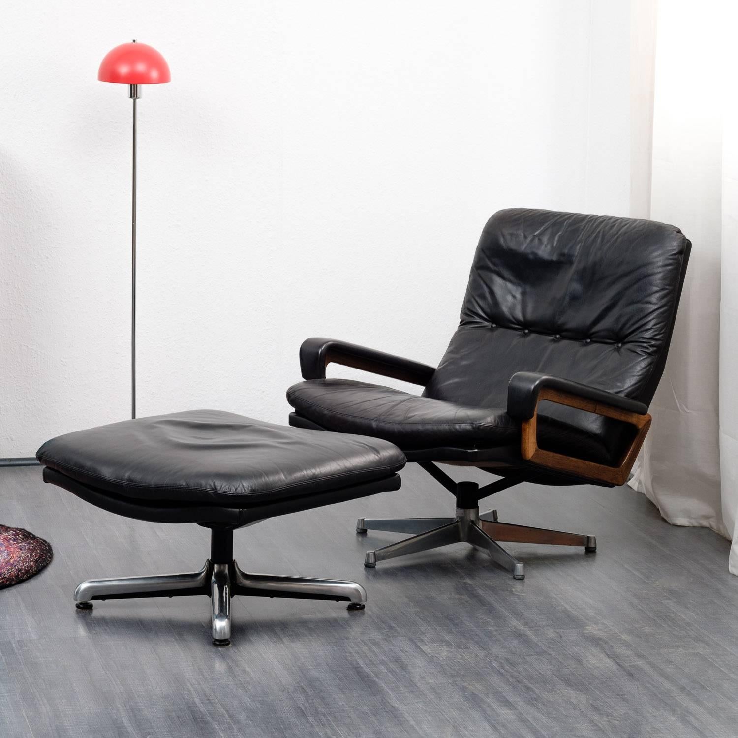 A Swiss made design classic from the 1970s:
The King chair by Strässle in black leather with rosewood armrests. High-quality materials and workmanship. The chair comes with the matching foot-stool. Good original condition with small traces of wear