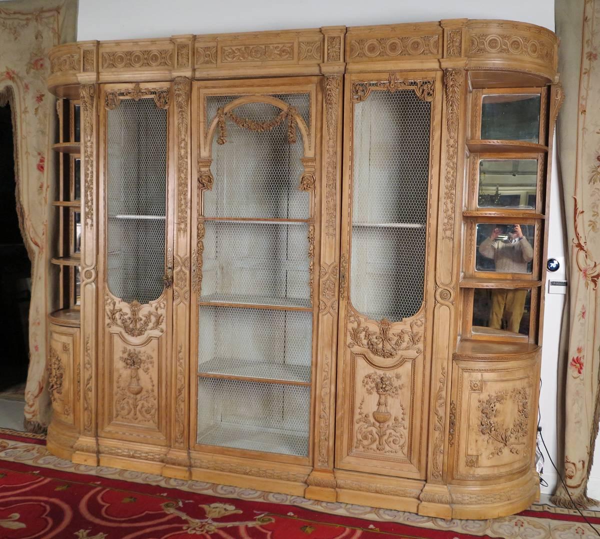 A rare Louis XVI carved beechwood
Biblioteque or breakfront cabinet
18th century

The multi sectional piece with a carved upper section over two shelved and mirrored back corner sections with a cupboard door at the bottom, the centre sections