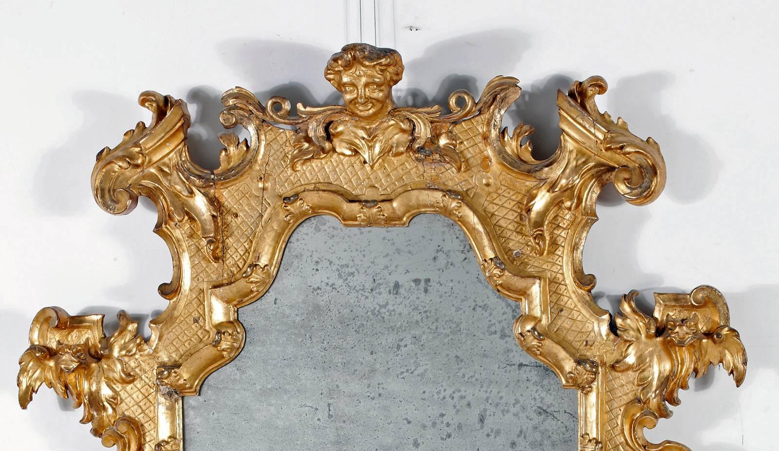 Fine & Rare Gilt-wood Mirror
Mid 18th Century (possibly English )

The oblong arched mirror plate within a molded frame carved with C-scrolls and foliage, surmounted with an elaborate crest and a central mask 

Height 52in.  Width 40in.

Provenance: