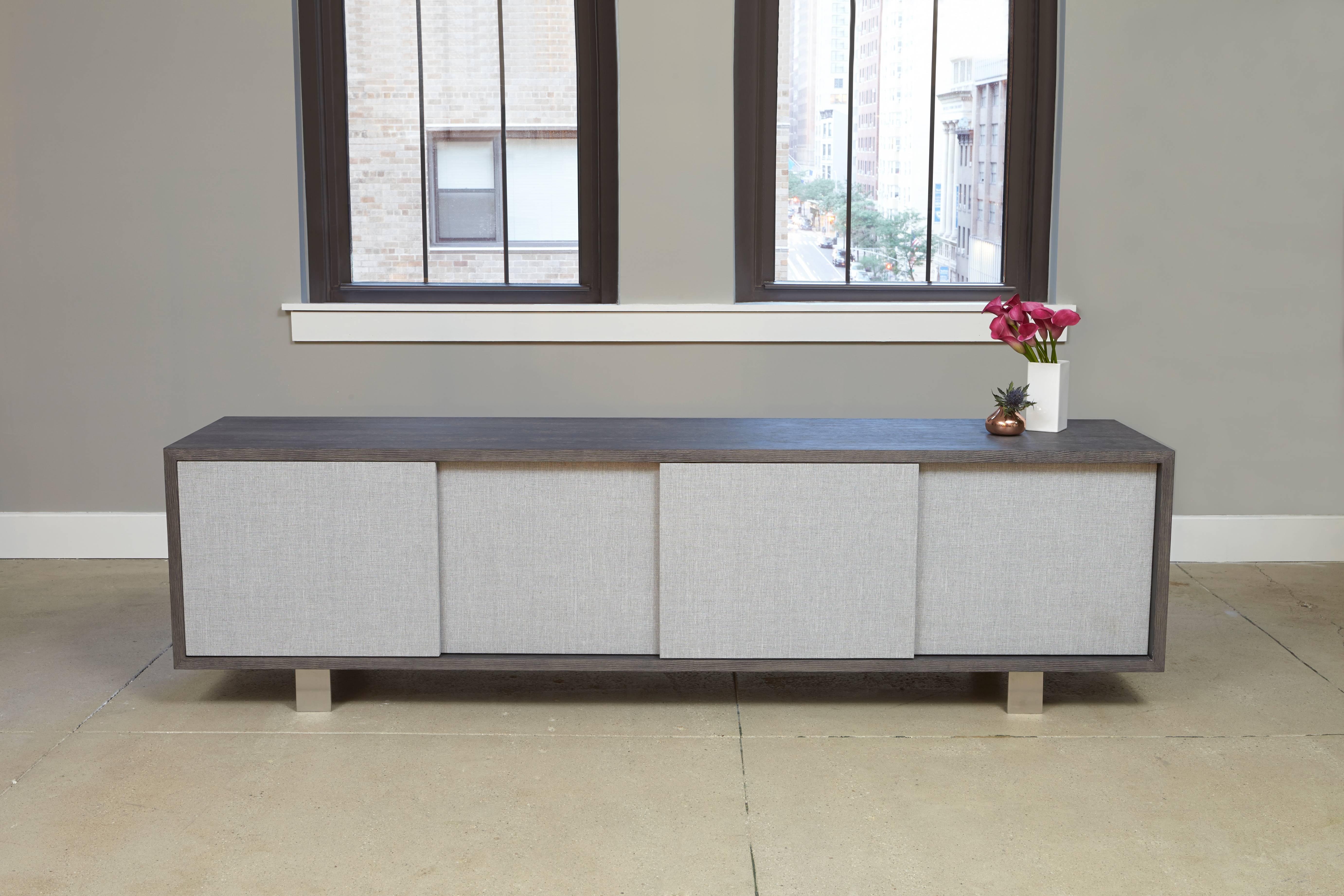 Featuring a simple, clean-lined metal and class construction, this lends a modern touch to your dining room or parlour ensemble. 

Available and shown in drift oak, stainless steel and maharam tek wall 1002 012.
Measure: 84 in x 19 in x 23 in