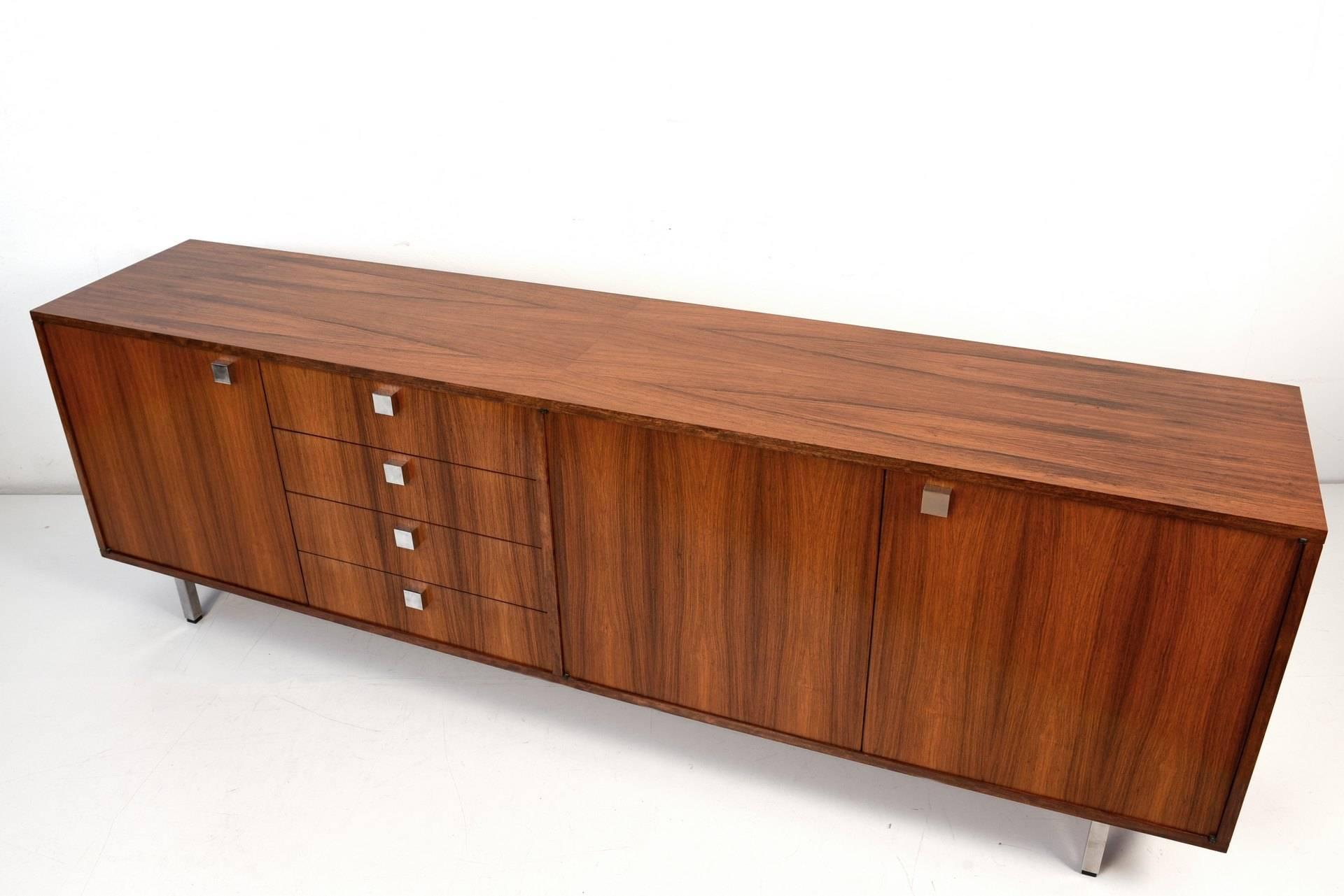 A vivid and decorative veneer picture is provided by this carefully produced cabinet furniture of the late 1960s. Charming details in geometric shapes are repeated in handles and base. Also the inside of the doors as well as the inlays have rosewood