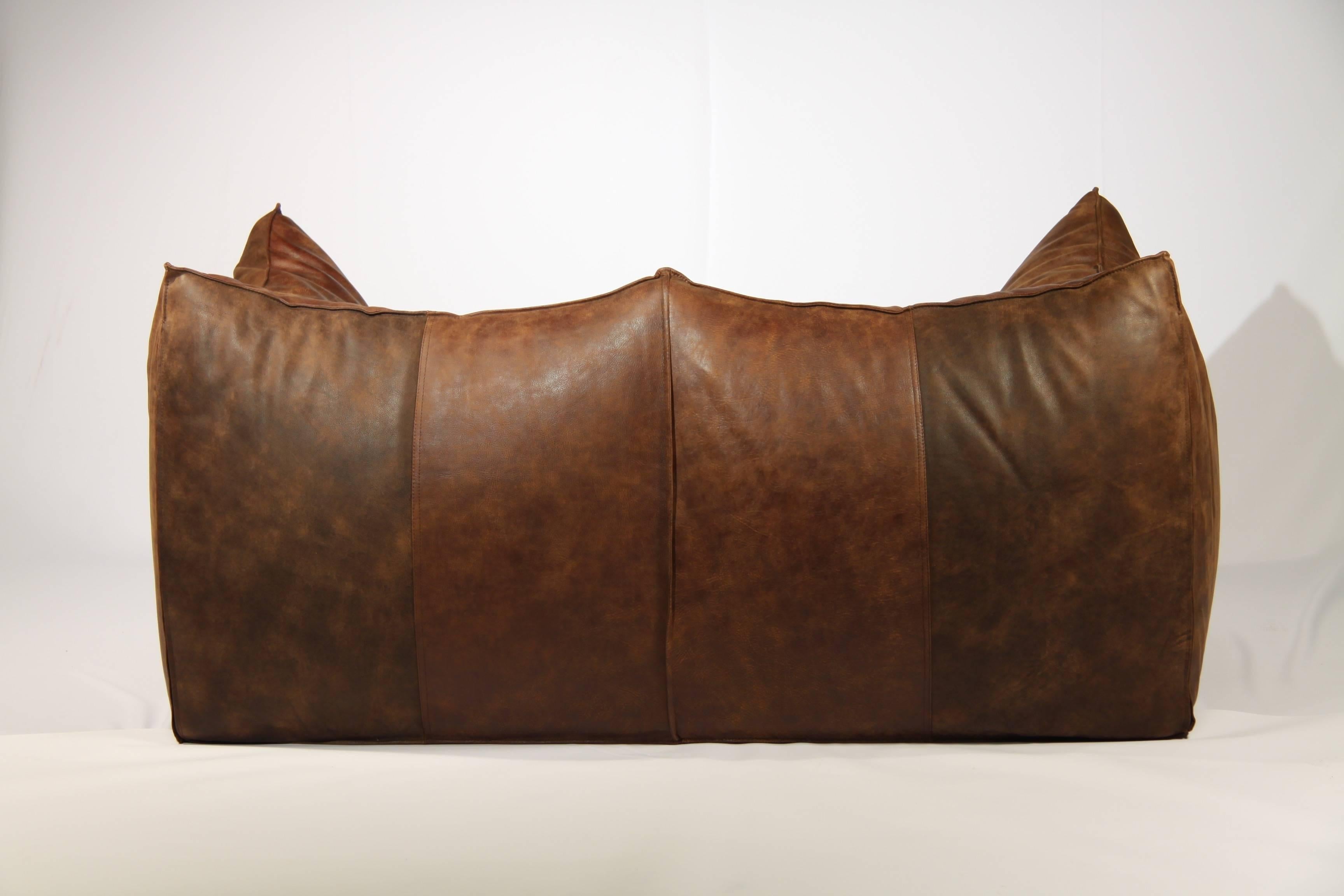 This leather sofa was designed by Mario Bellini and produced by B&B Italia during the 1950s. The icon of modern design won the “Compass D’oro International Award” in 1979. The loveseat is upholstered with thick, brown leather and the bottom base is