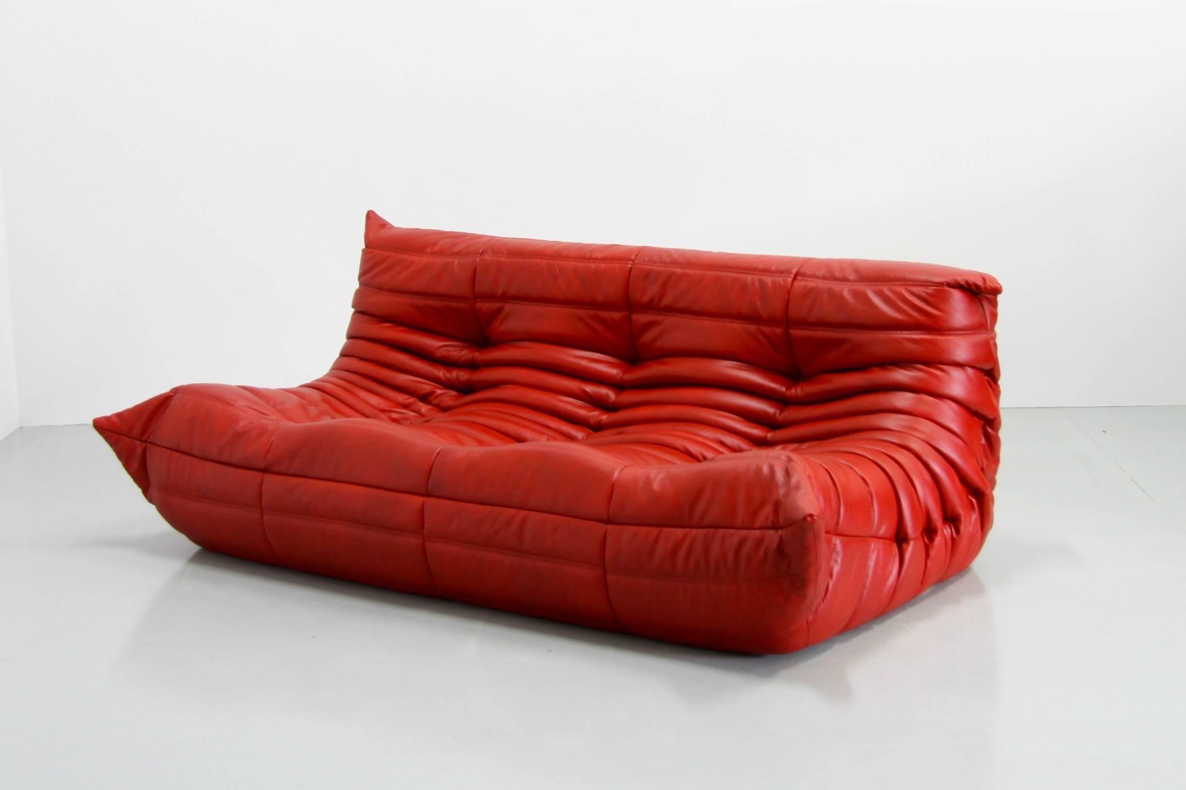 This Togo living sofa was designed by Michel Ducaroy in 1974 and was manufactured by Ligne Roset in France. It has been reupholstered in genuine red leather and is a 3-seater couch (70 x 176 x 102 cm). It has the original Ligne Roset logo.