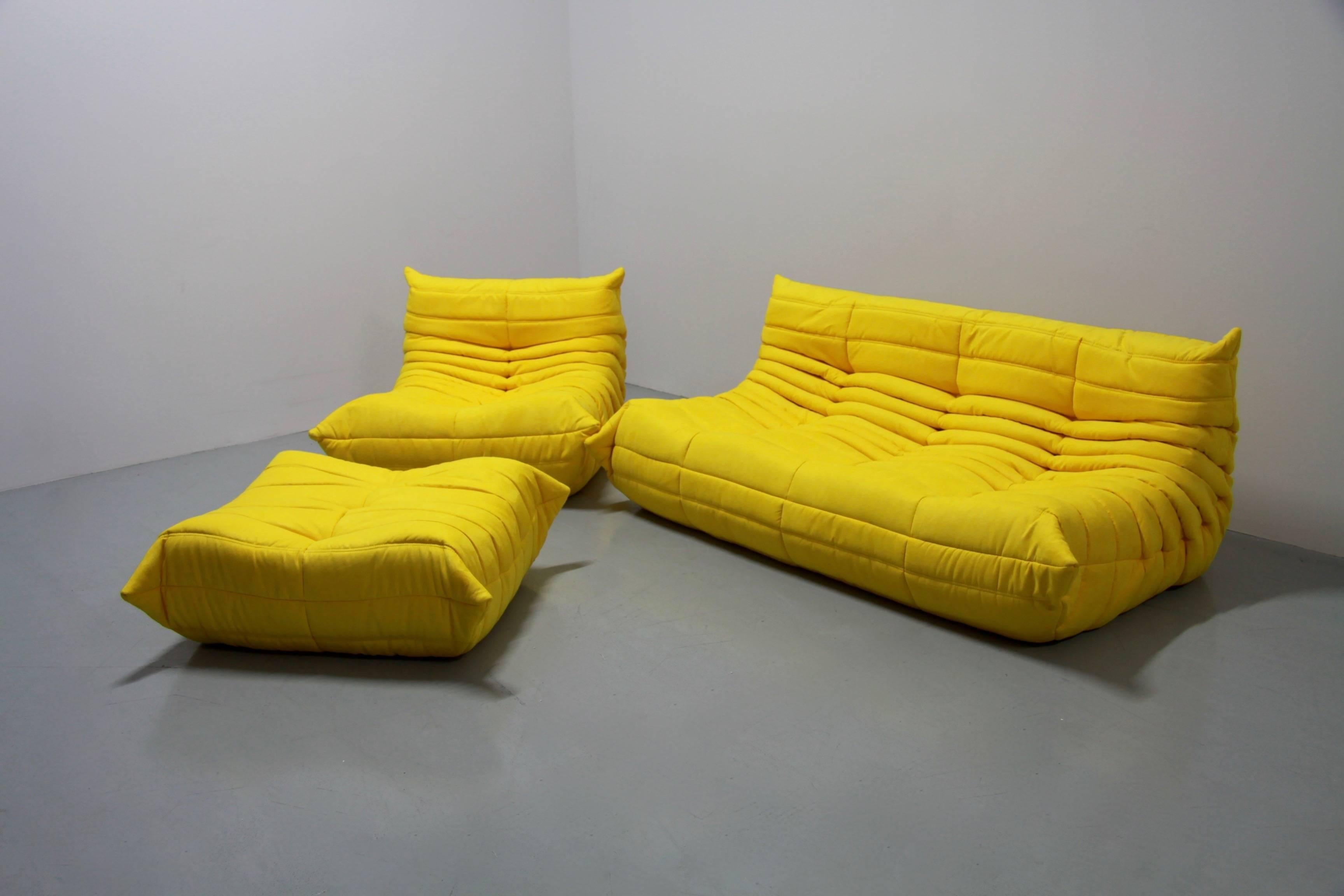 This Togo living room set was designed by Michel Ducaroy in 1974 and was manufactured by Ligne Roset in France. Each piece has the original Ligne Roset logo and genuine bottom. It has been reupholstered in yellow high quality Italvelutti microfibre