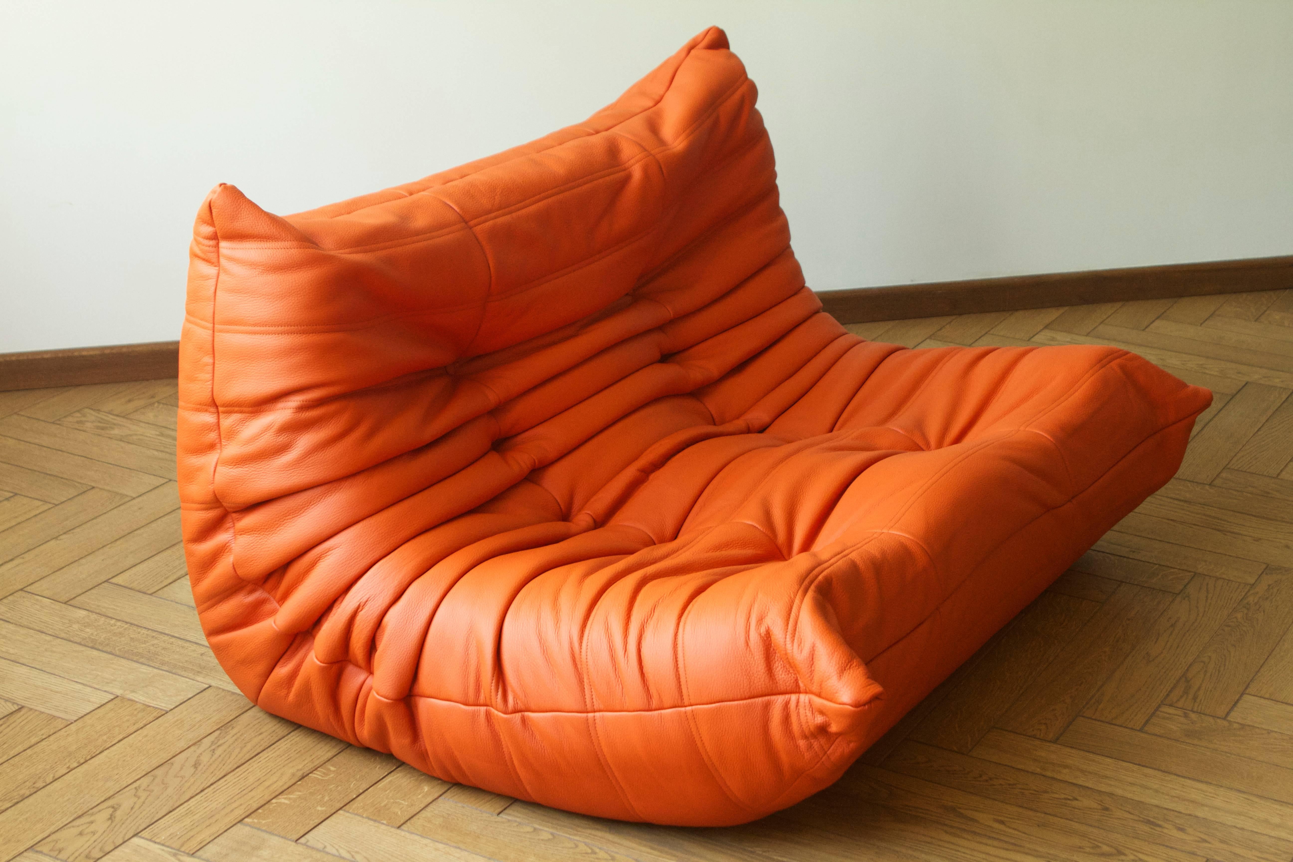 This two-seat Togo sofa (70 x 131 x 102 cm) was designed by Michel Ducaroy in 1973 and was manufactured by Ligne Roset in France, produced in the 1990s. It has been reupholstered in orange leather and it features the original Ligne Roset logo at the