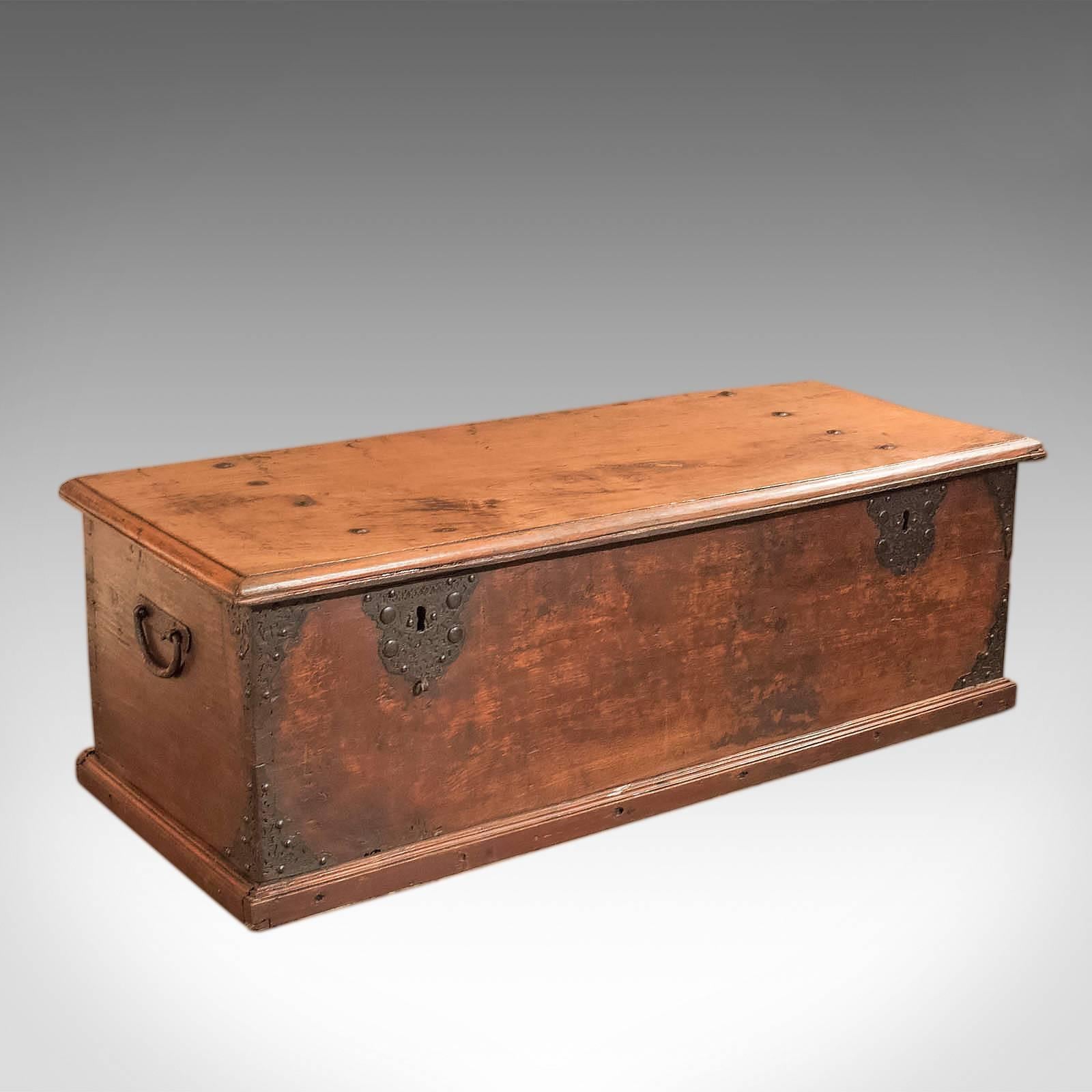 This is an antique, colonial hardwood chest dating to the early 19th century.

Raised on a plinth base, this large and heavy trunk is made from dense and solid hardwood boards with attractive graining and patina; part of the lid moulding retaining
