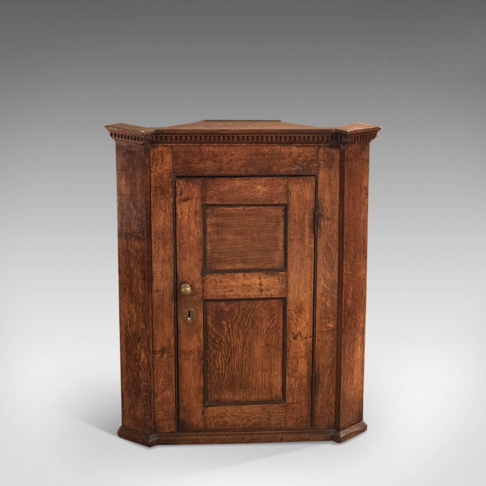 This is an antique, Georgian corner cabinet dating to circa 1750.

A super example of Provincial country furniture from the mid-18th century, this small corner cabinet displays a delicious warm patina and good graining in the English oak