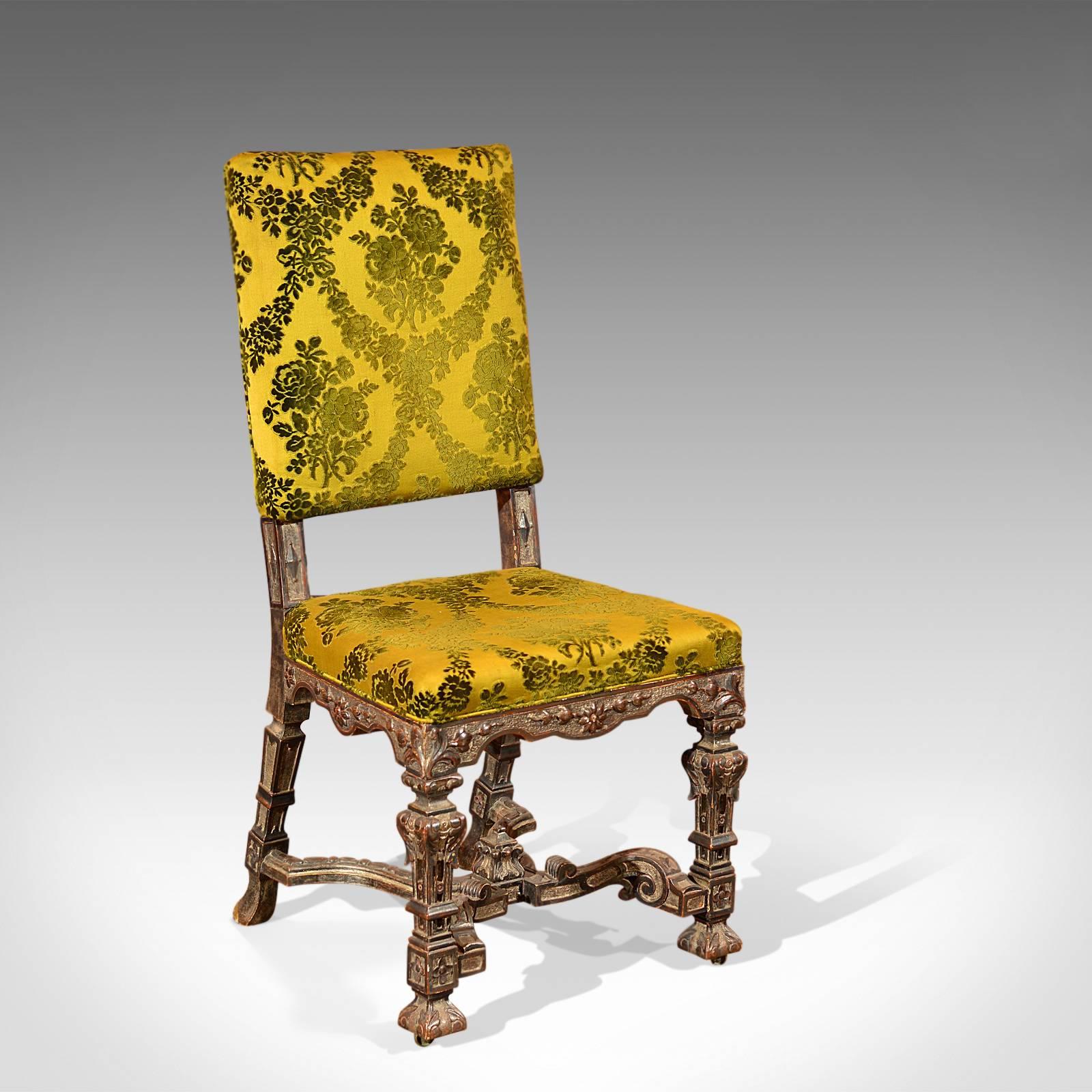 This is an antique, French side chair dating to circa 1900.

The heavily carved frame displays Gothic overtones in the serpentine seat rails, square section baluster legs and extravagant 'X' frame stretcher topped with inverted carved finial. The