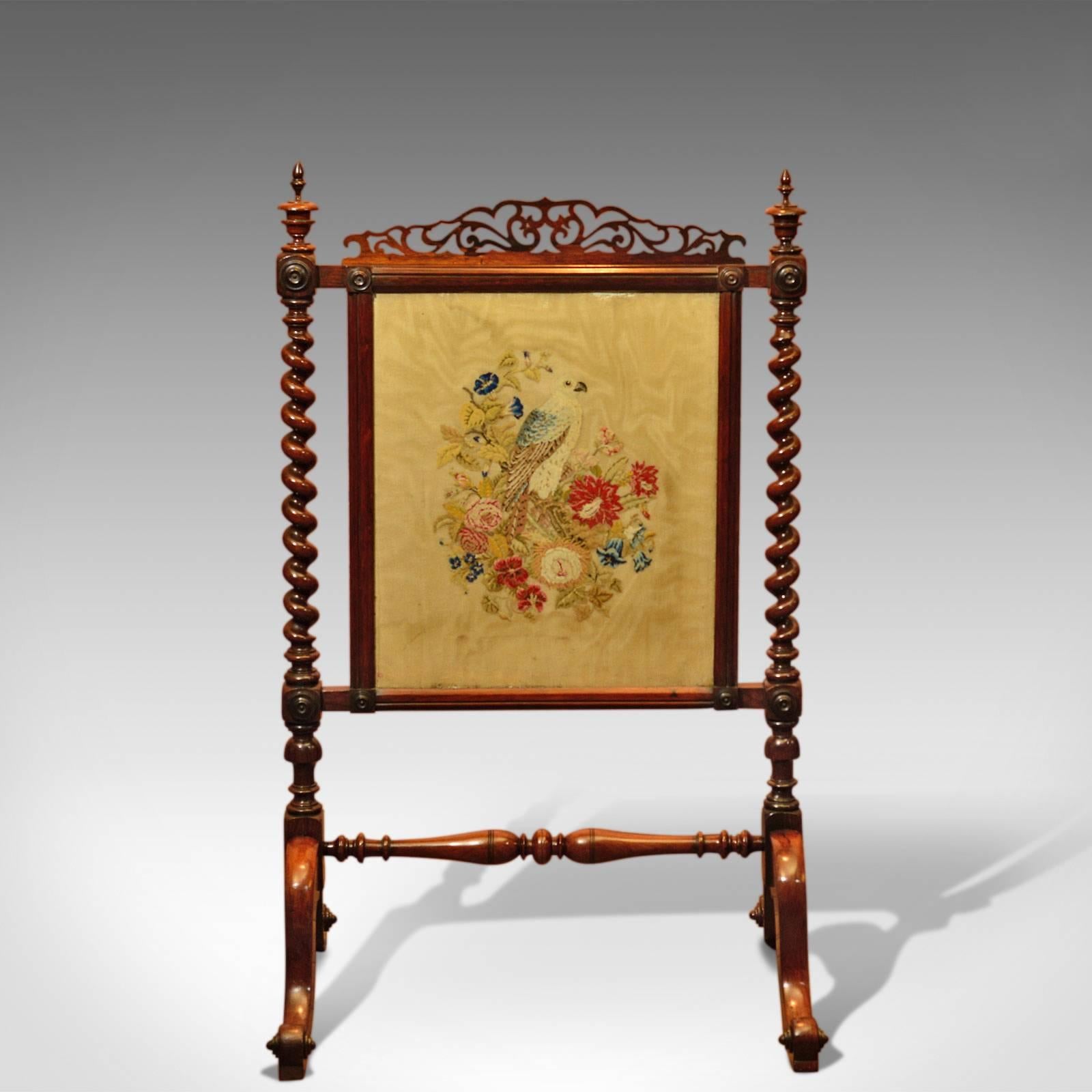 This is an antique, Victorian fire screen dating to circa 1850.

Fine quality and constructed in rosewood with great attention to detail, this screen displays a deep lustrous shine and wonderful antique patina.

Rising on scrolled feet, the