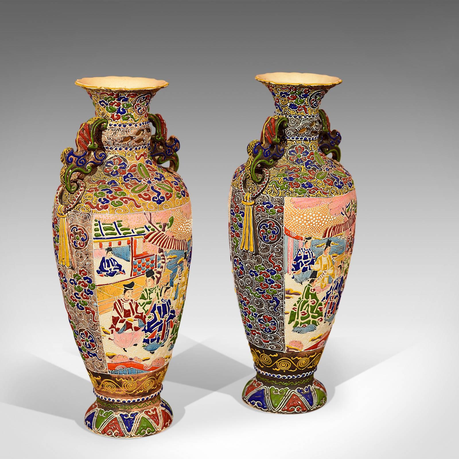 This is a pair of Japanese Moriage antique vases.

Colorful in raised enamel, glazed slipware or 'moriage', this profusely decorated pair of urns depict charming oriental scenes framed with foliage and floral detail interspersed with stylised bead