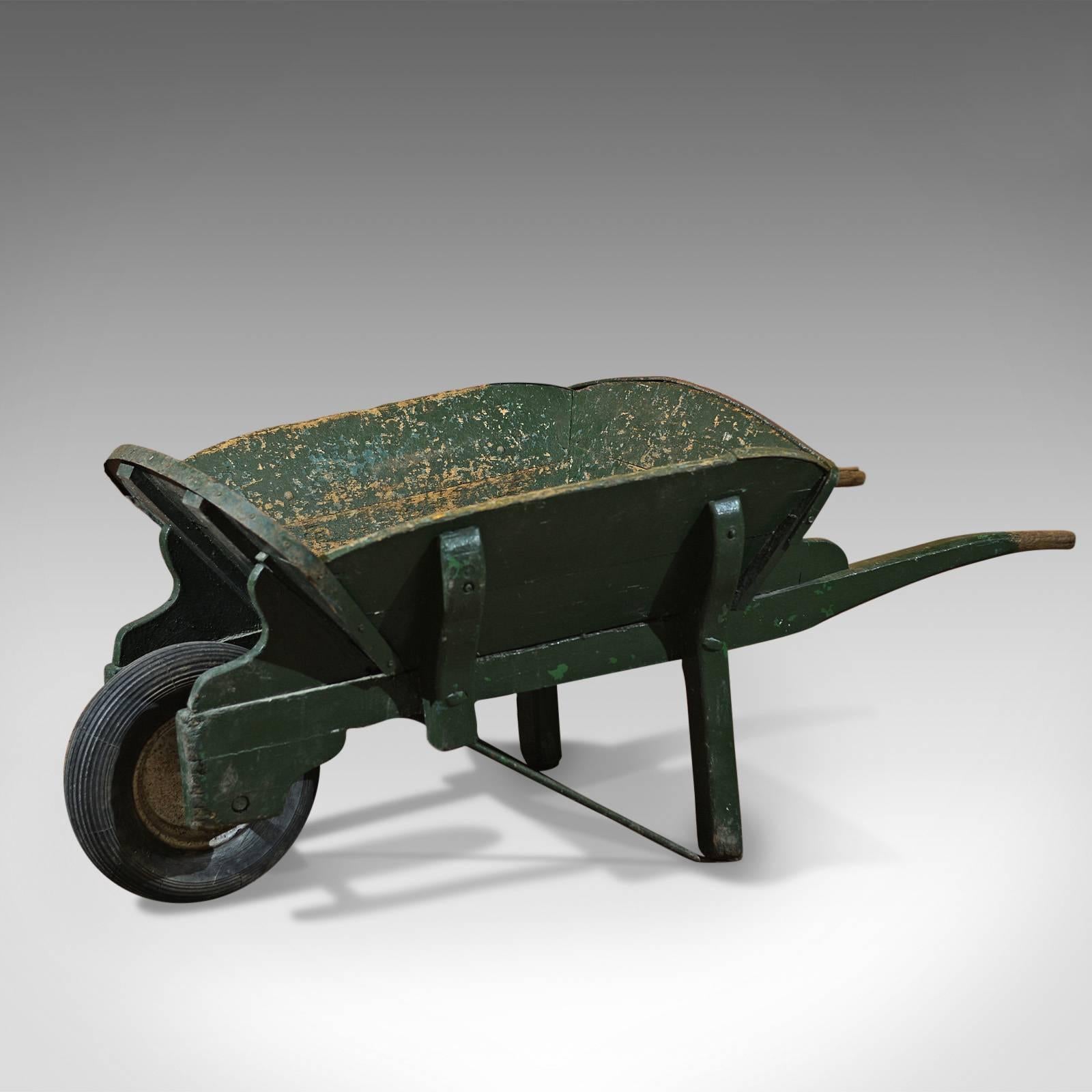 This is an antique, green Victorian gentleman's wheelbarrow.

A large and fine example, sturdily constructed from ash, iron bound and strengthened by robust struts, supports and brackets, it carries with it all the hallmarks of a long and useful