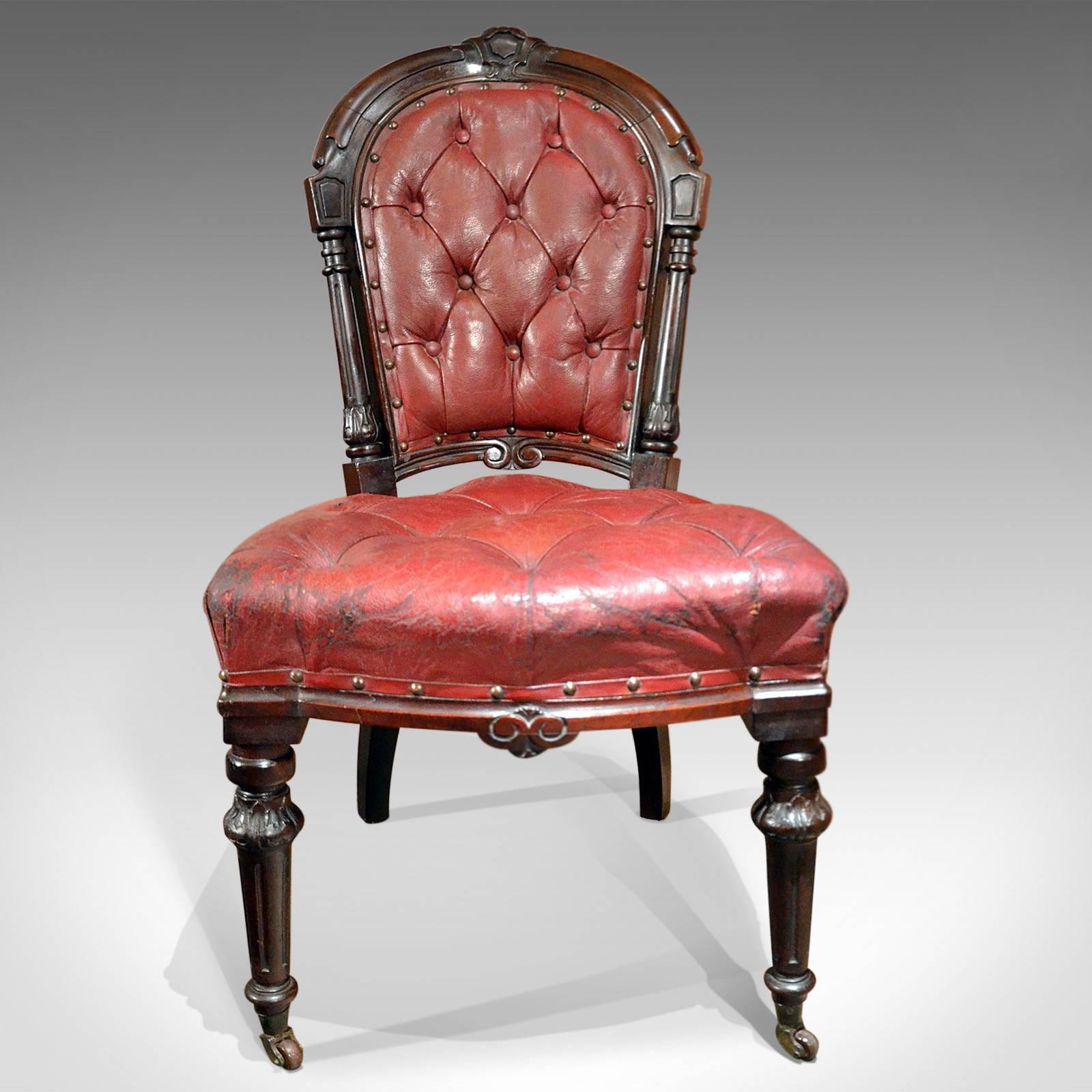 This is an English Late Regency button-backed library chair in a beautiful aged burgundy red leather.

Rich with, and retaining, an historical charm and grace this elegant chair, dating to circa 1830, draws influence and motif from ancient Rome as